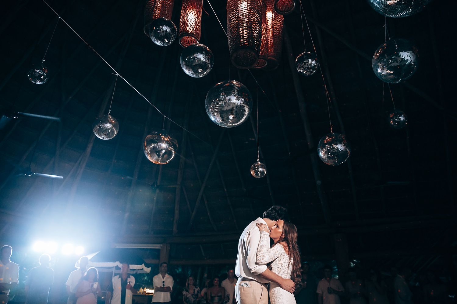 Romantic dance scene under hanging glass orbs and moody lighting at wedding reception.