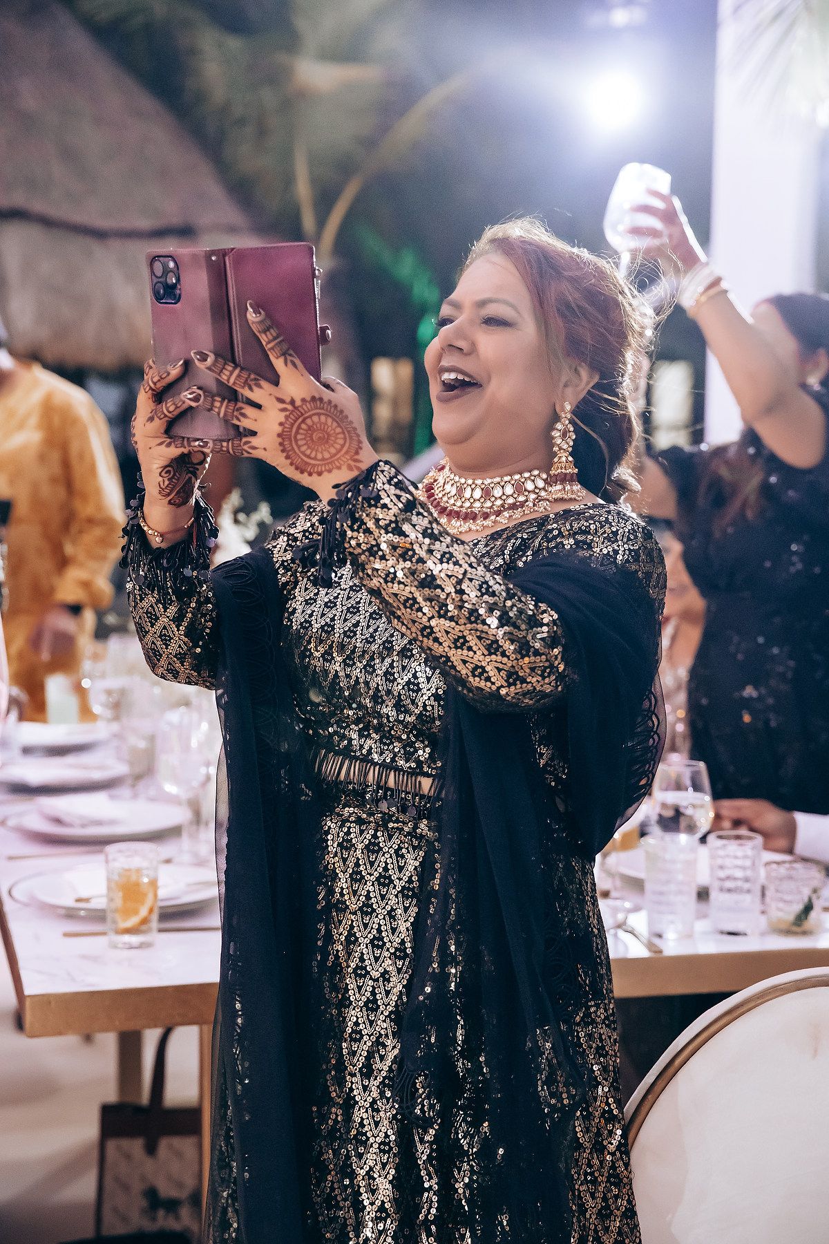 Person wearing an ornate black and gold embellished dress celebrating at an elegant reception.