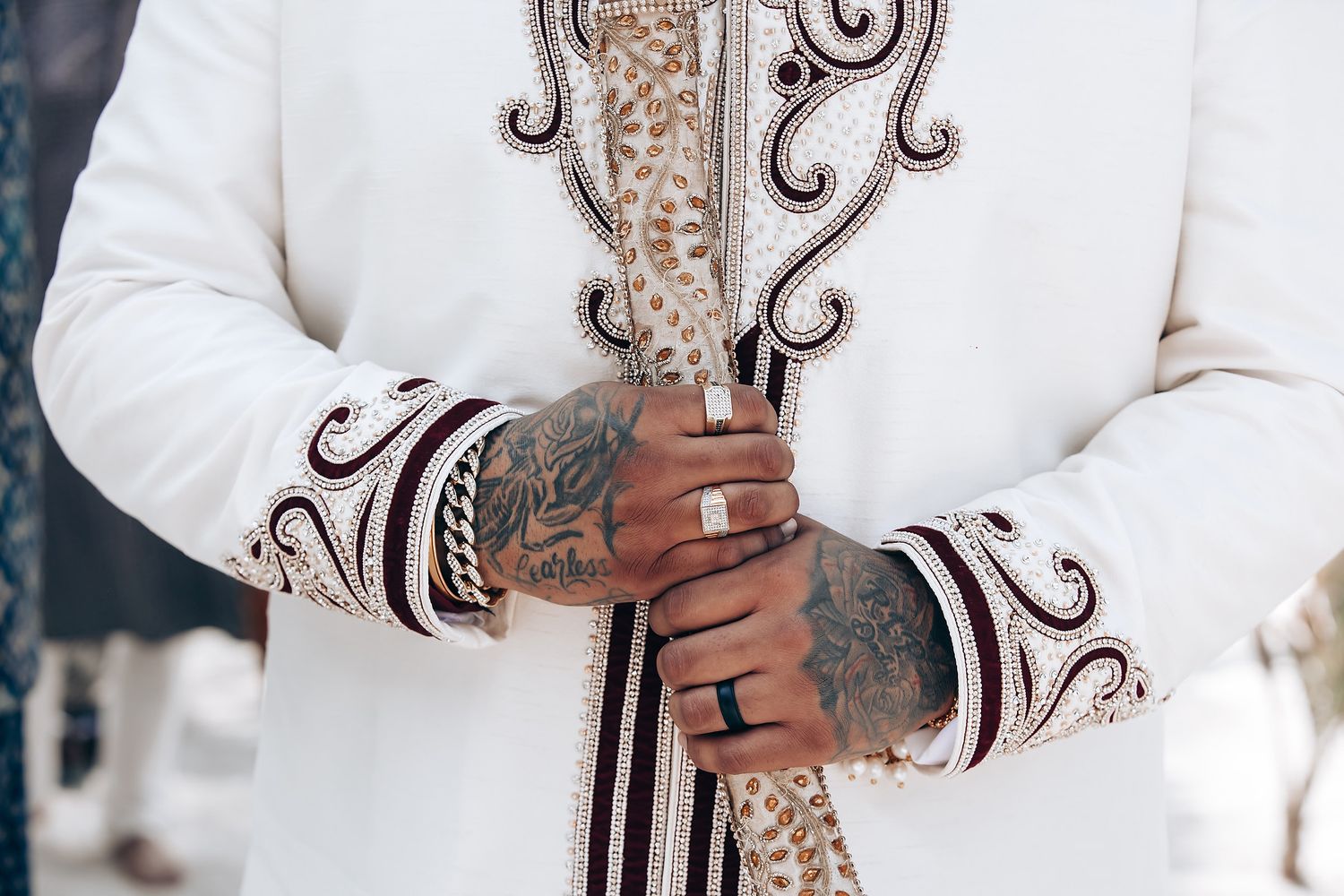 Detailed view of ornate embroidery on white wedding sherwani with gold accents.
