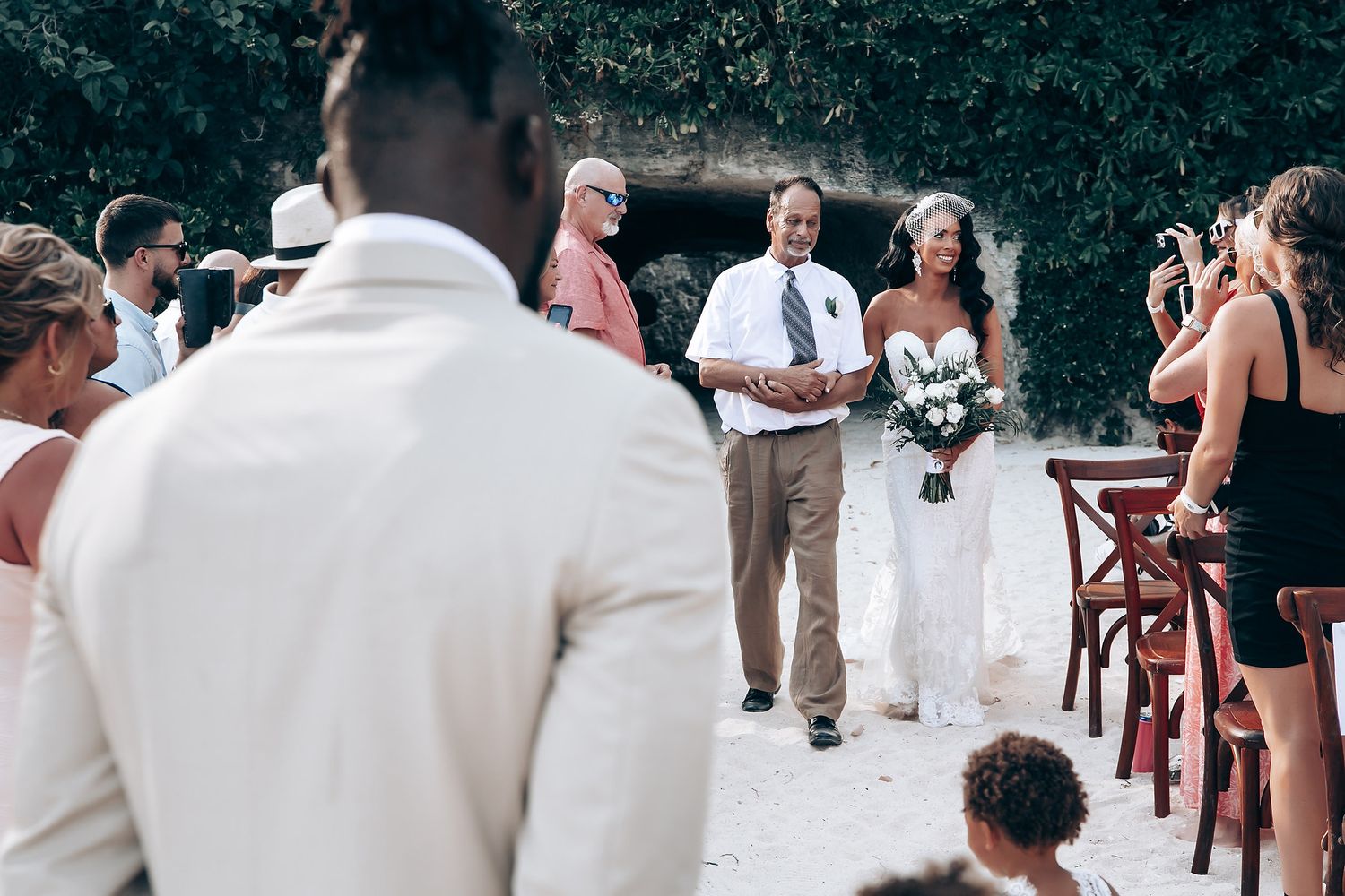 A wedding reception crowd dances together outdoors in summer attire with white and dark clothing.