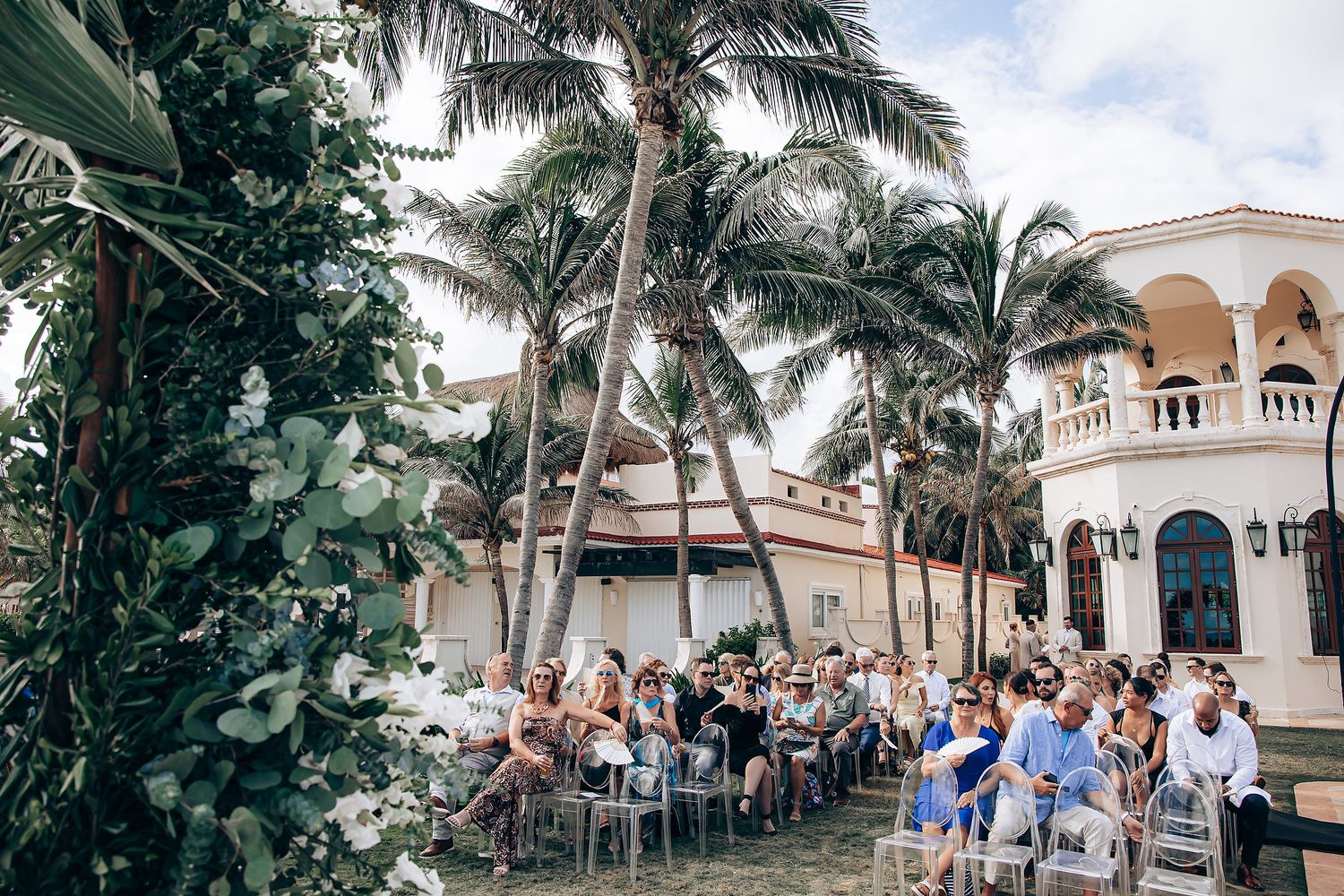 Panoramic view of a beachfront wedding venue with palm trees and white Mediterranean-style architecture.