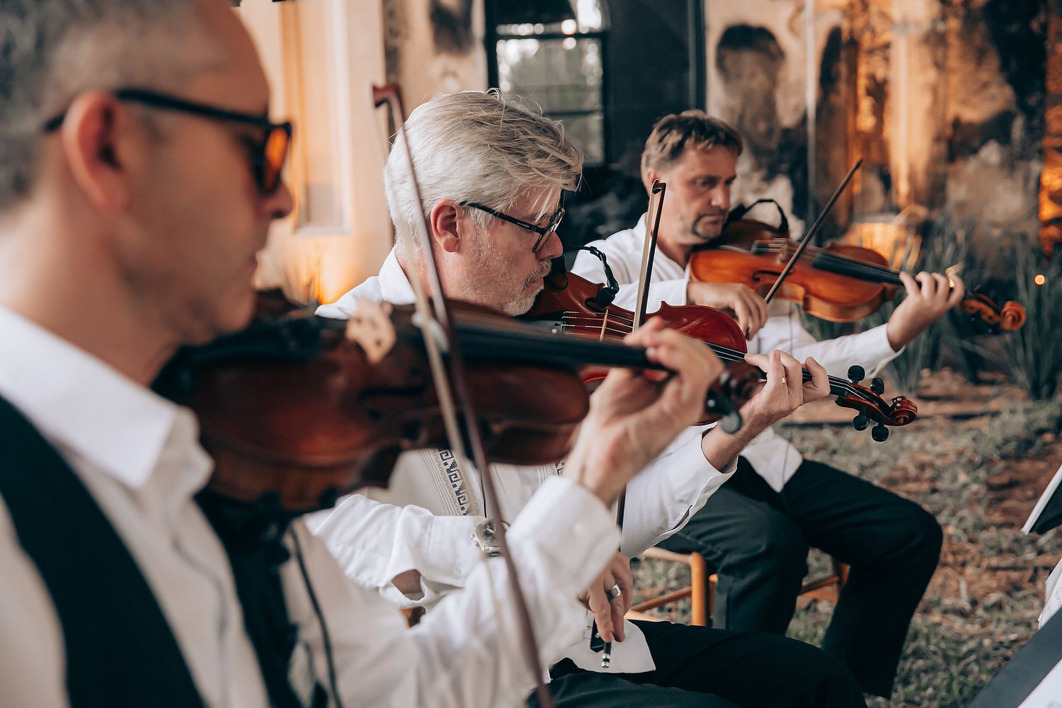 A group of musicians in formal attire perform together while holding wine glasses during an elegant event.