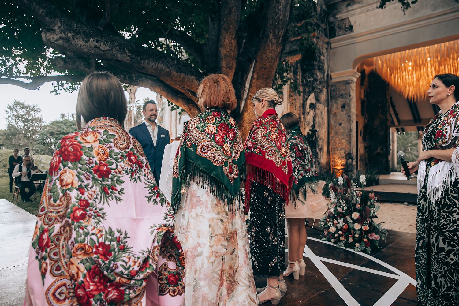 Wedding party celebrates outdoors with sparklers creating a magical nighttime atmosphere at a rustic venue.