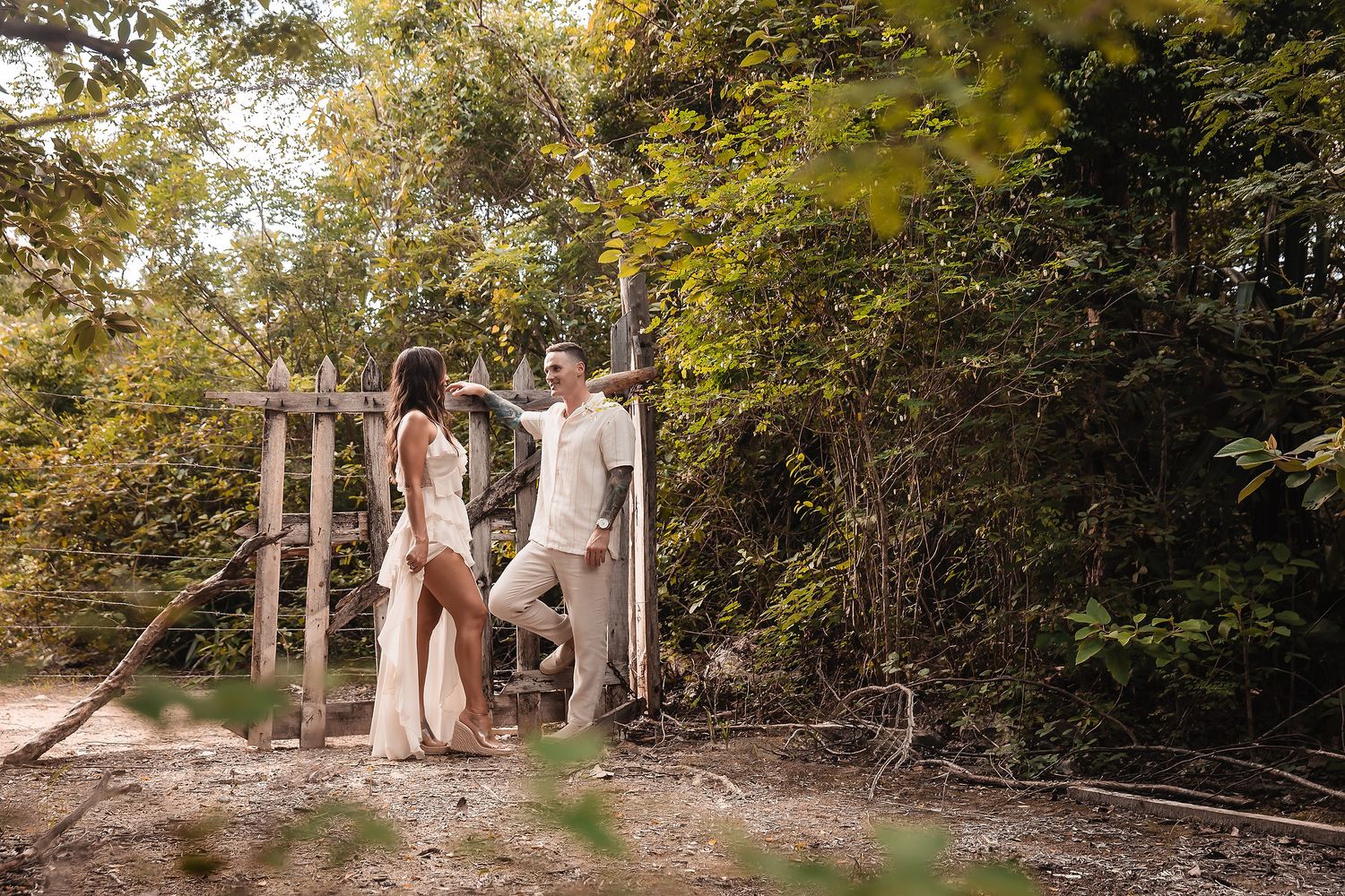 Two people share candid moments together on a rustic woodland path.