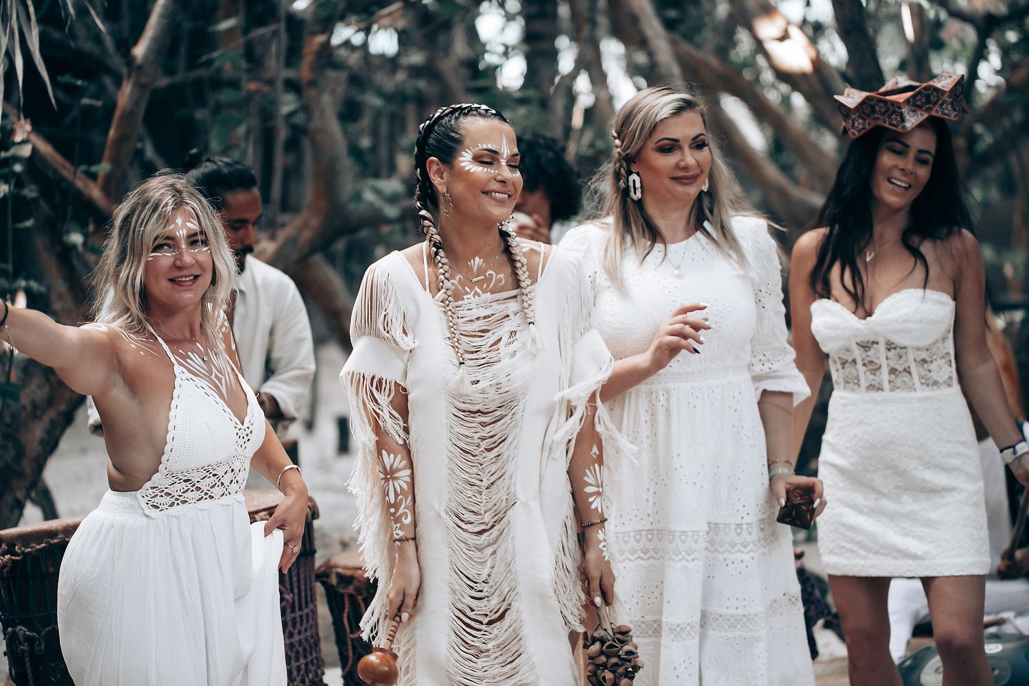 Wedding celebration on the beach with guests wearing flowing white outfits.