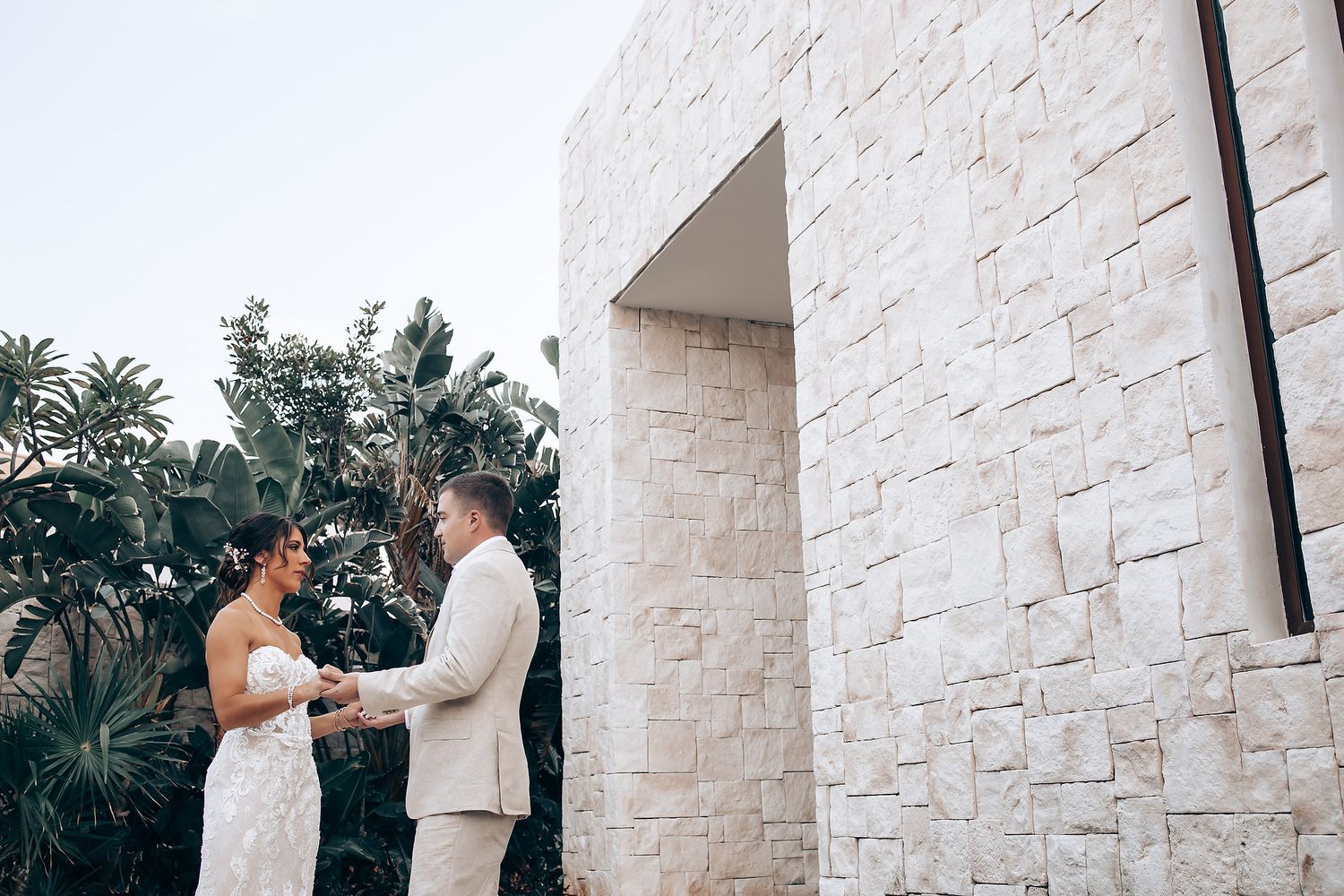 Wedding ceremony setup with white stone walls and tropical landscaping.
