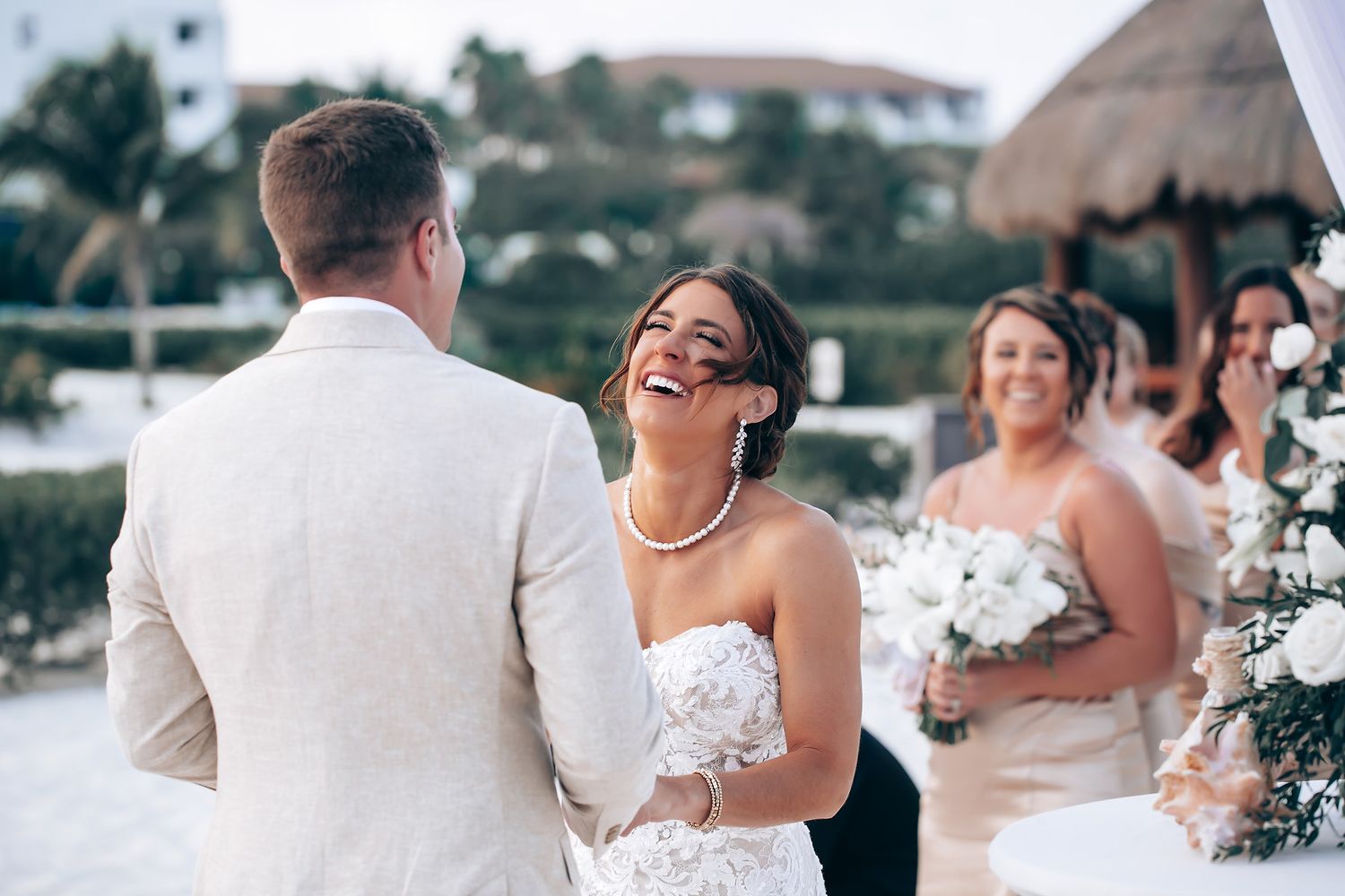 Elegant beach wedding ceremony setup with white chairs and floral arrangements by the ocean.