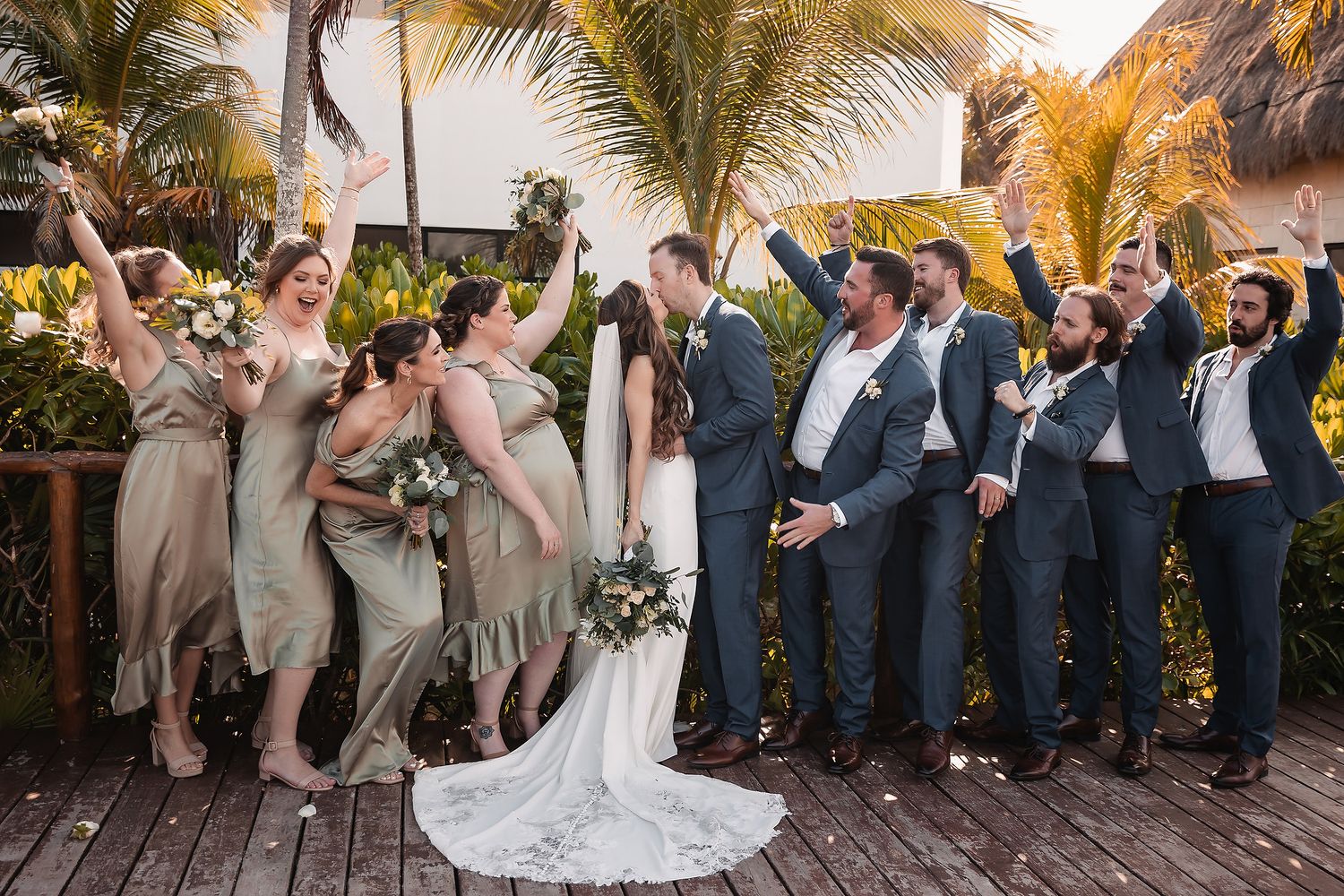 Wedding party celebrating outdoors under palm trees with confetti and joyful expressions.