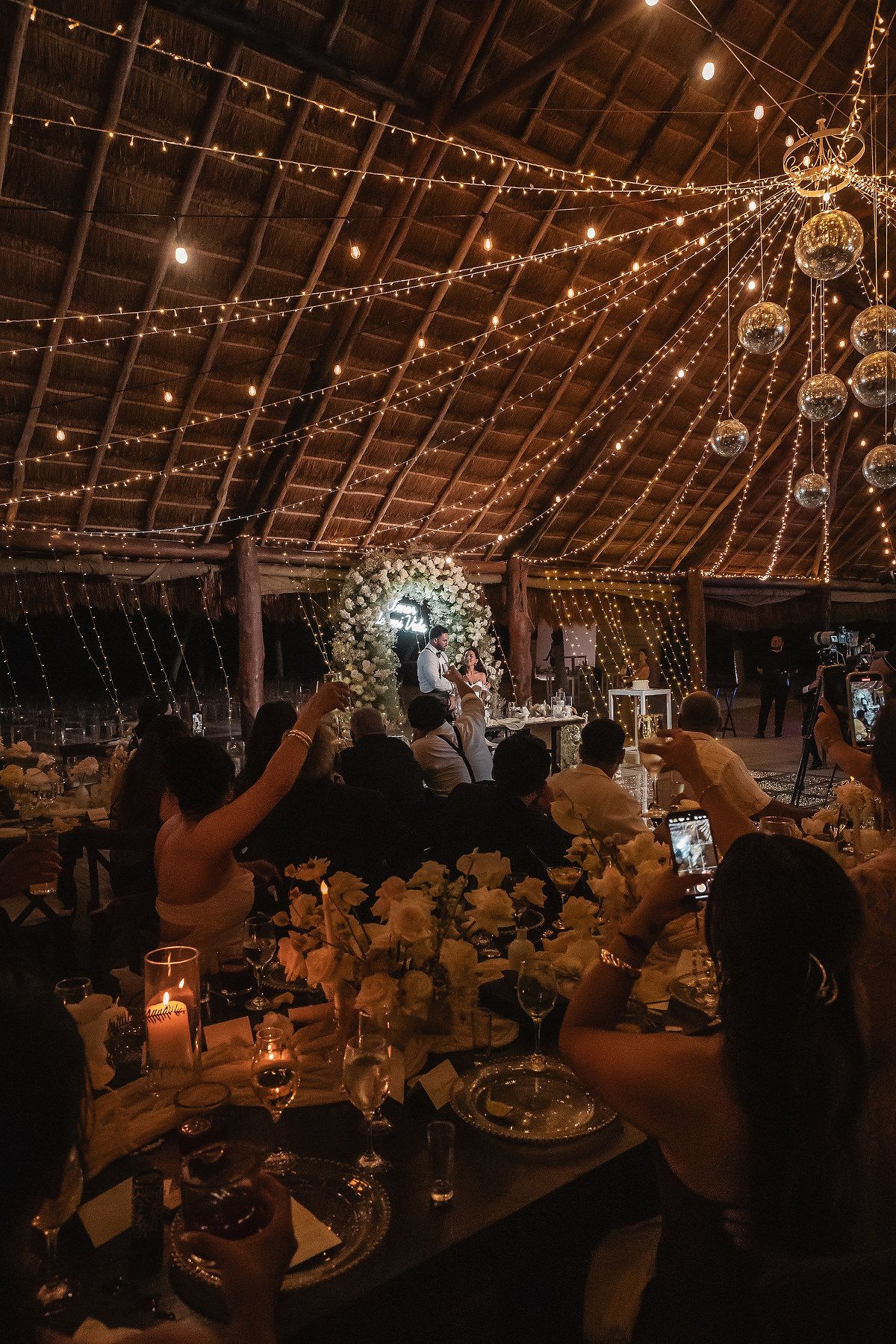 Wedding reception hall decorated with romantic string lights and elegant table settings.