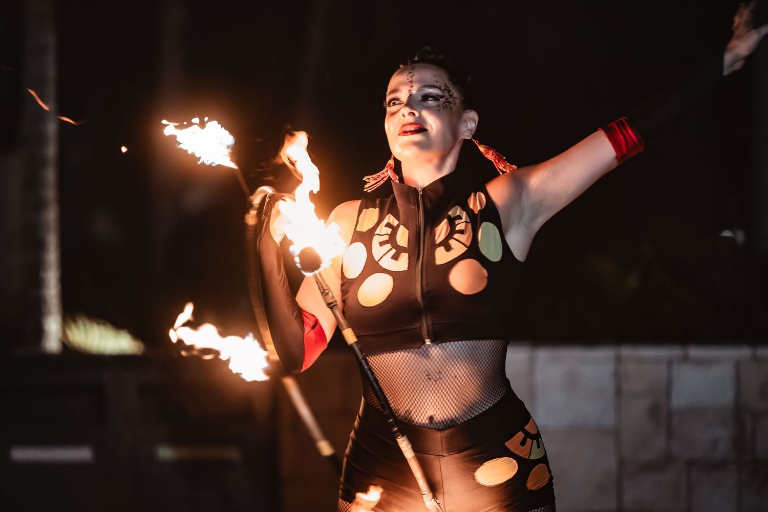 Fire dancers perform with flaming torches against a dark night backdrop.