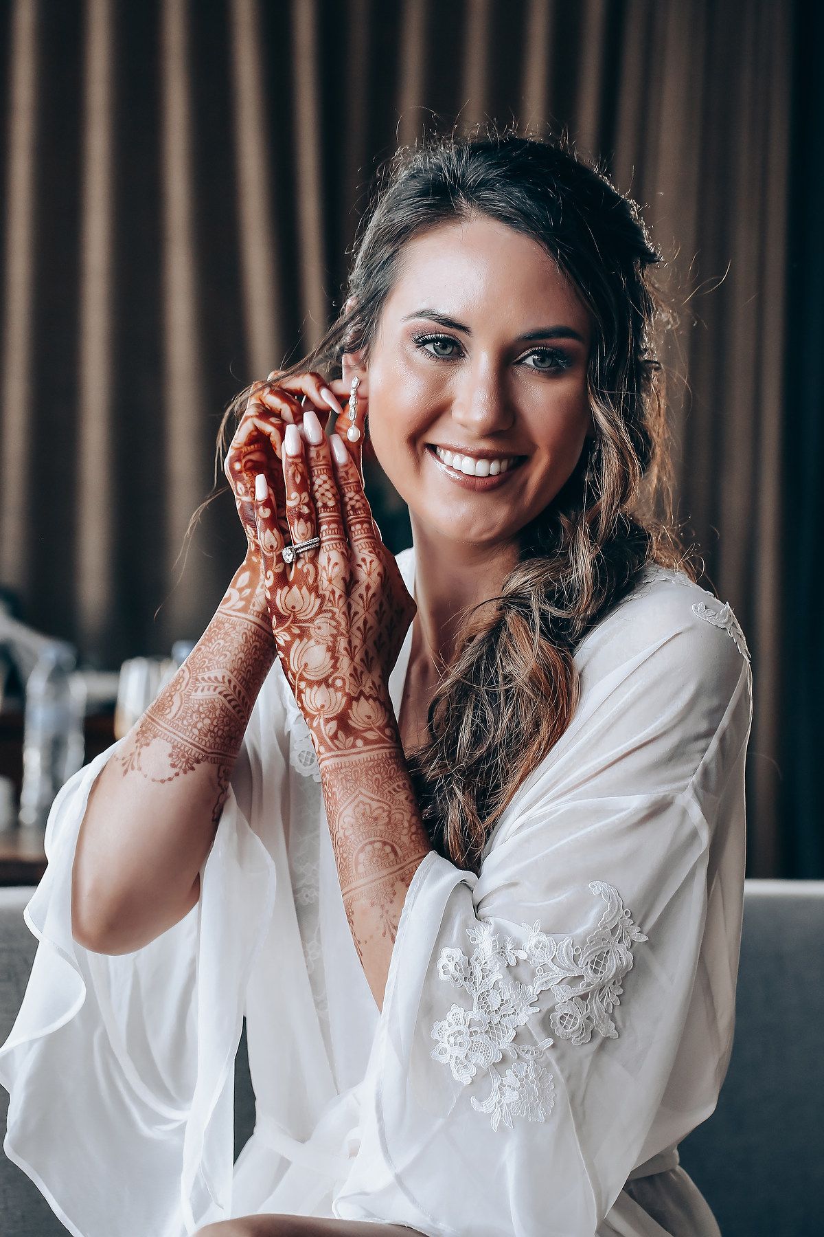 Bride in white robe shows her decorated hands with traditional henna designs in a series of four photos.