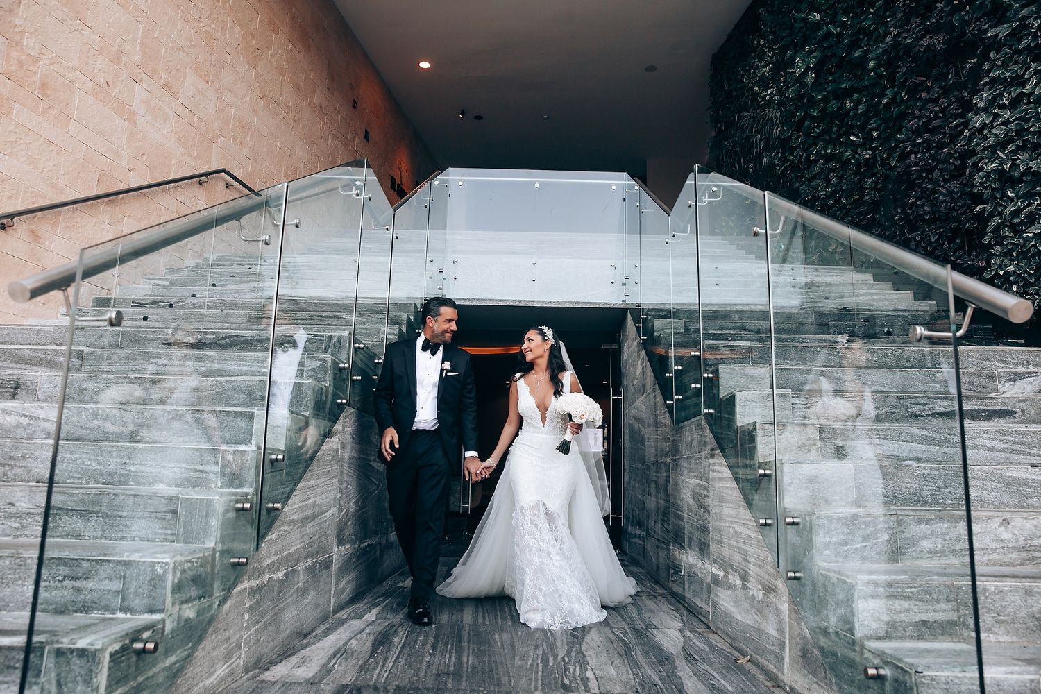 Modern wedding venue hallway with reflective surfaces and dramatic lighting.
