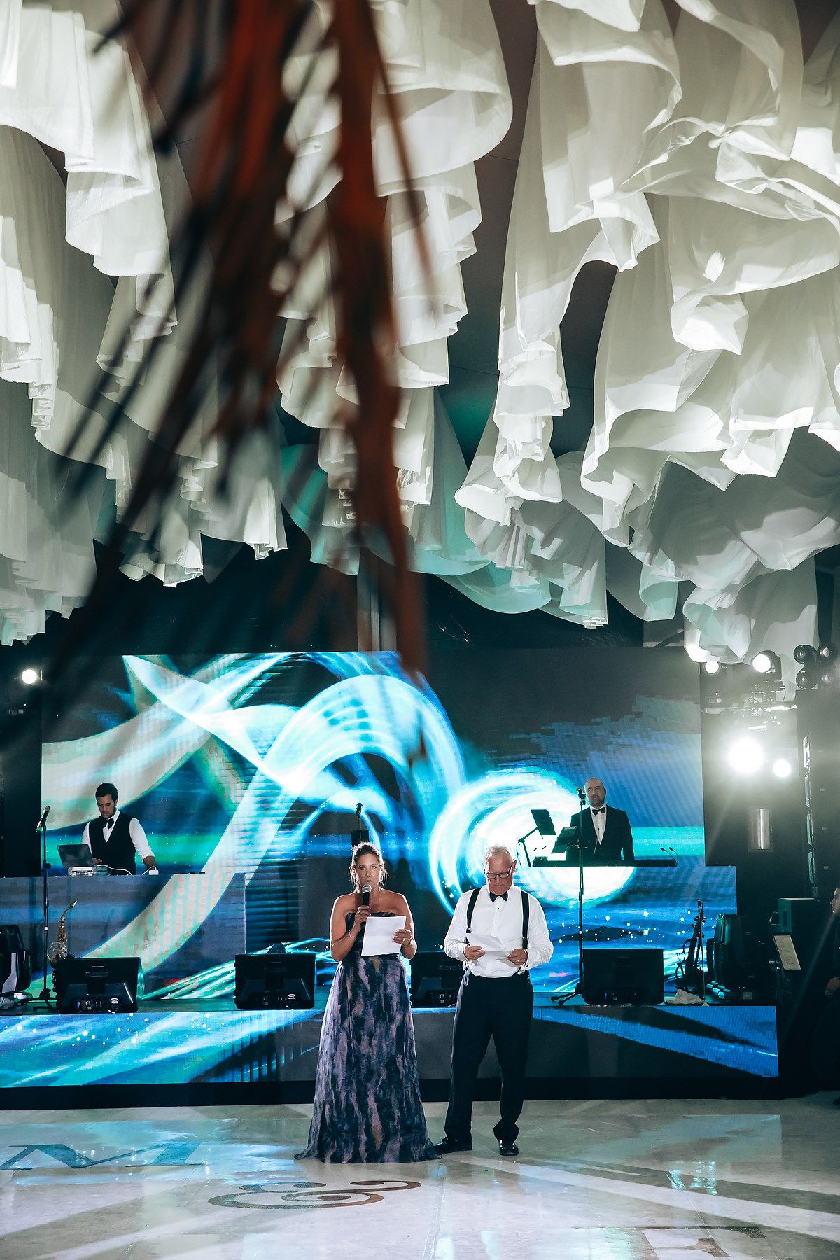 Performance on a dance floor with blue lighting and white draped ceiling decor.