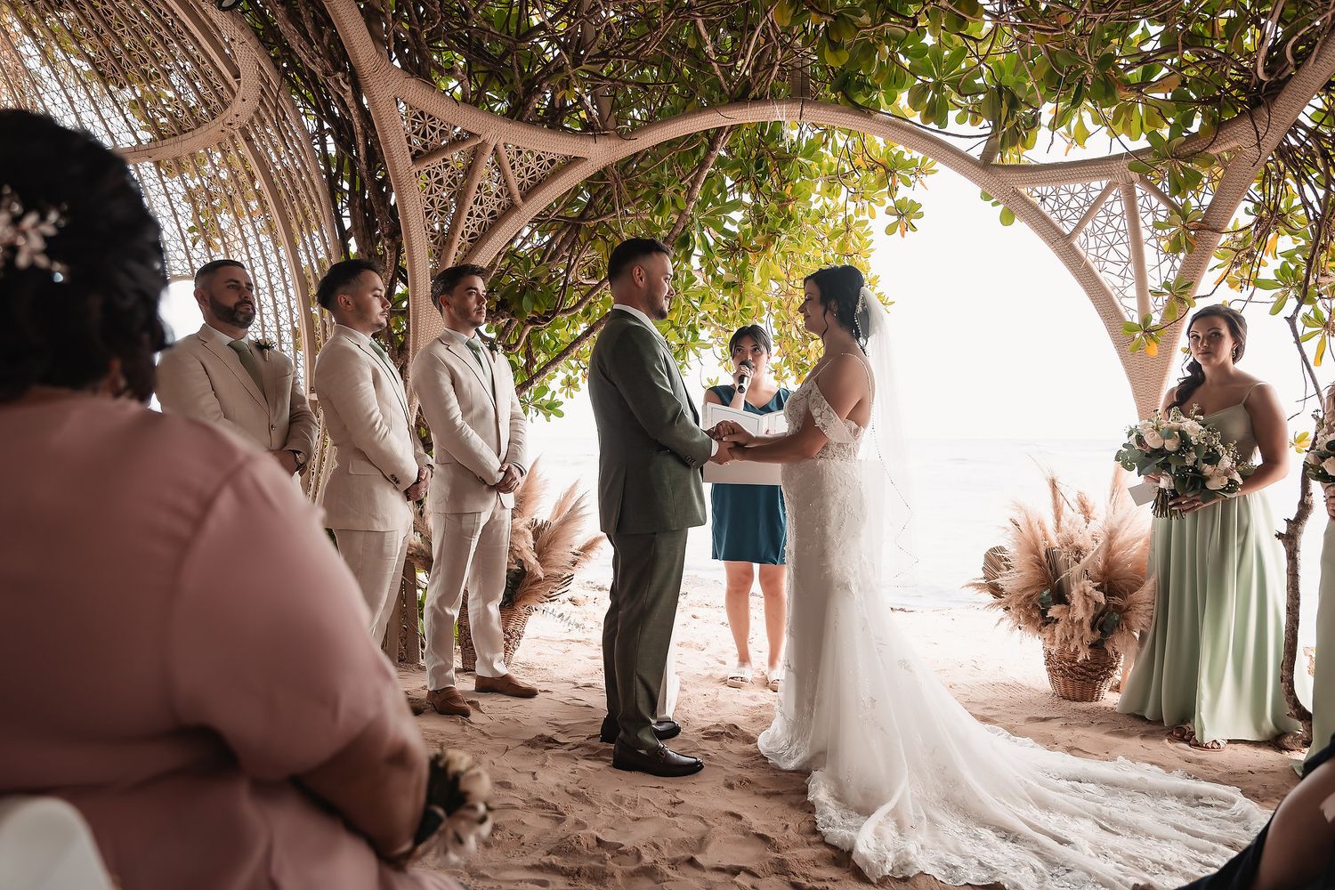 Wedding celebration under a rustic wooden gazebo surrounded by lush greenery.