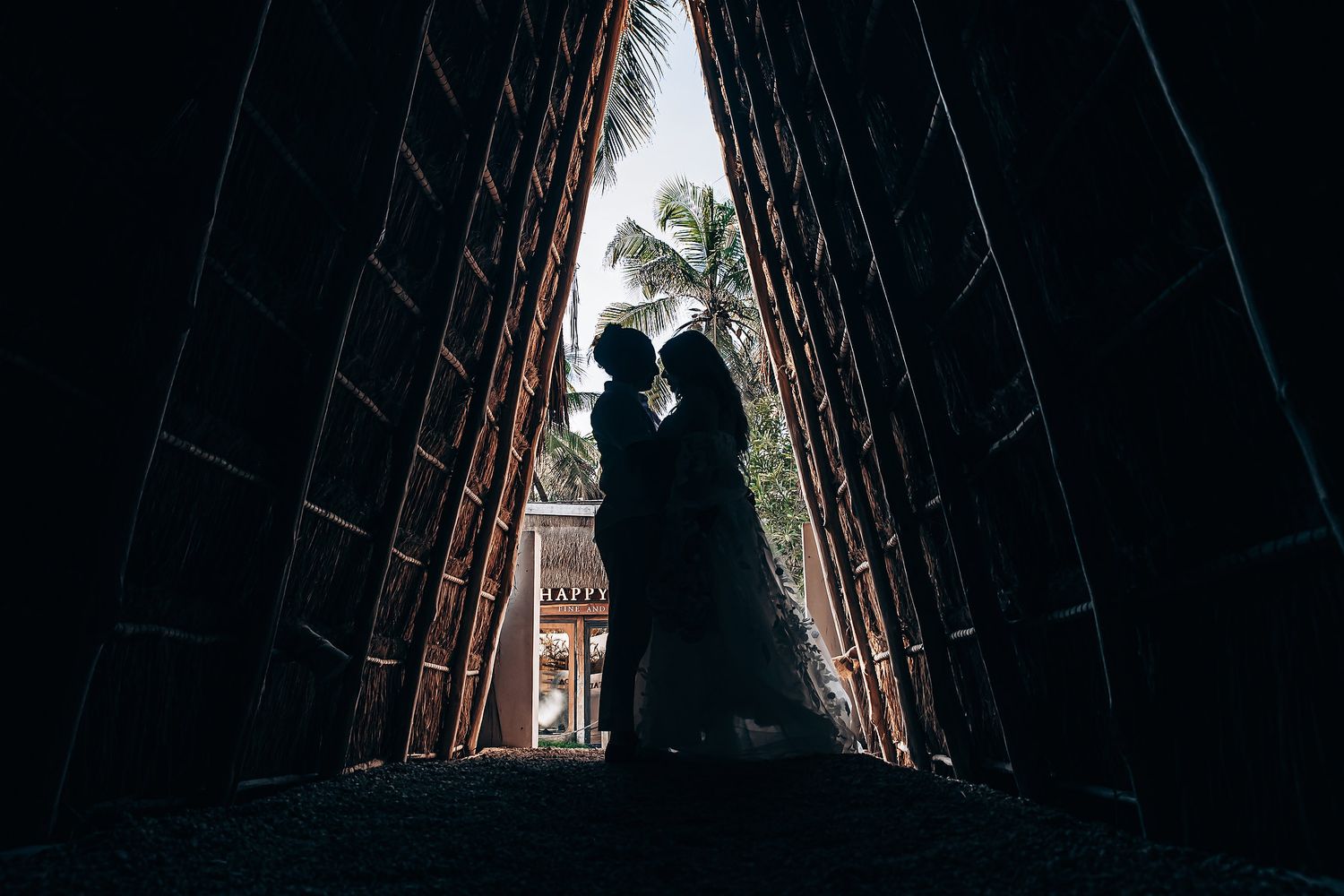 A silhouetted couple stands in a dramatic archway creating a romantic wedding portrait.
