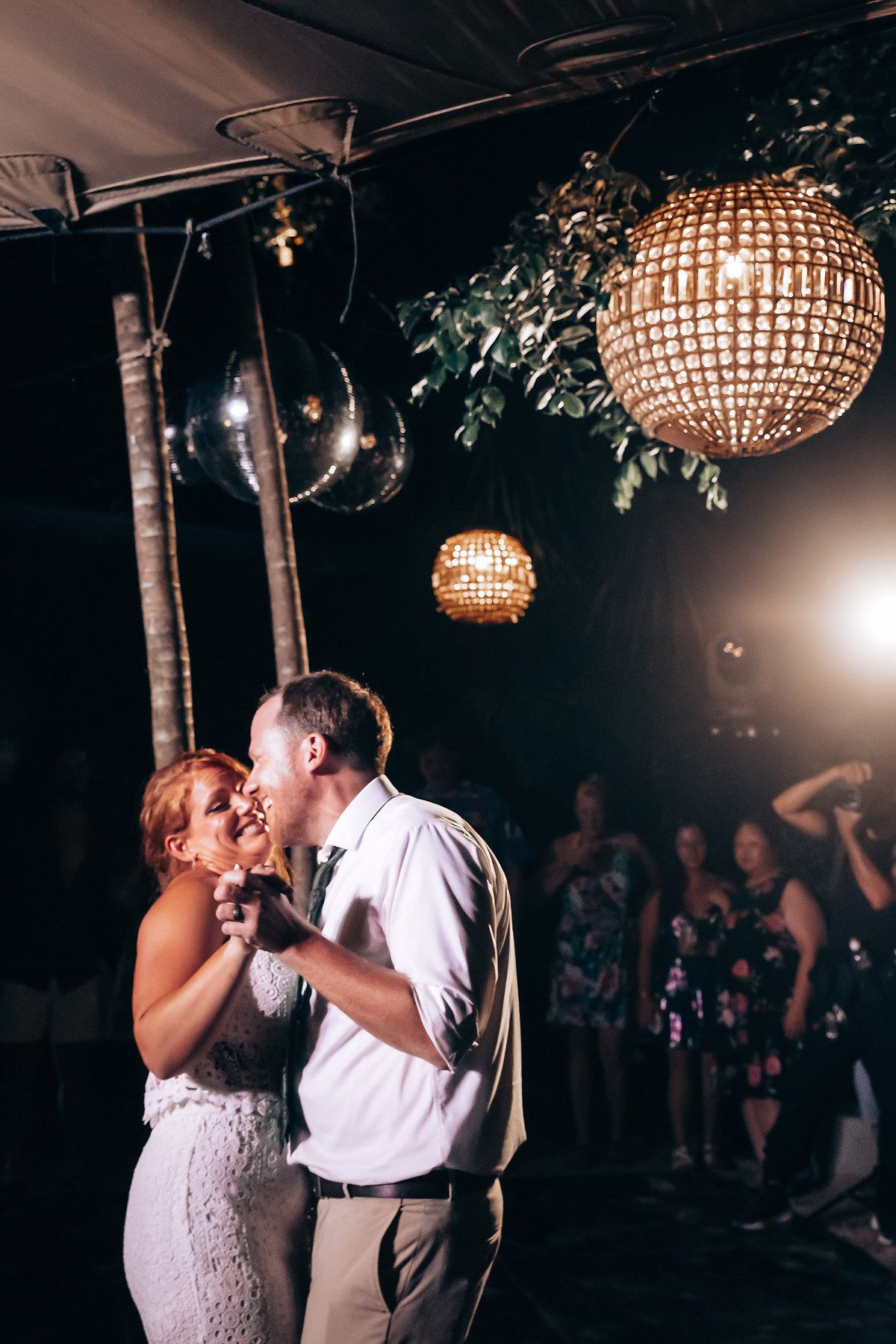 Couple sharing their first dance under crystal chandeliers at a wedding reception.