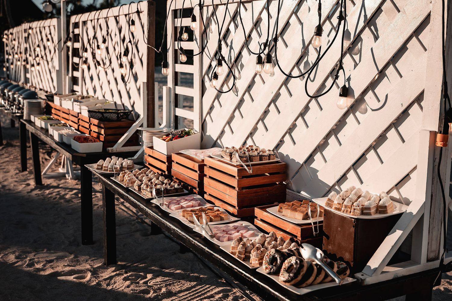 Rustic outdoor seafood display with wooden crates and fresh shellfish arranged on metal tables at a beachside restaurant.