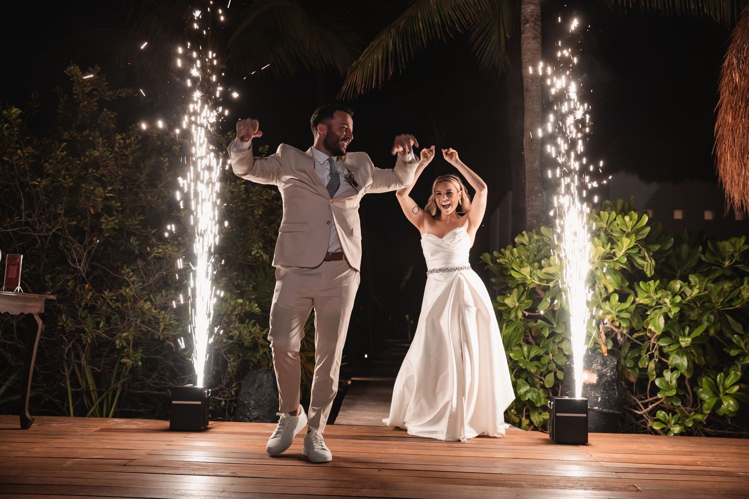 Bride and groom first dance entrance with dramatic sparkler fountains at outdoor evening wedding reception.