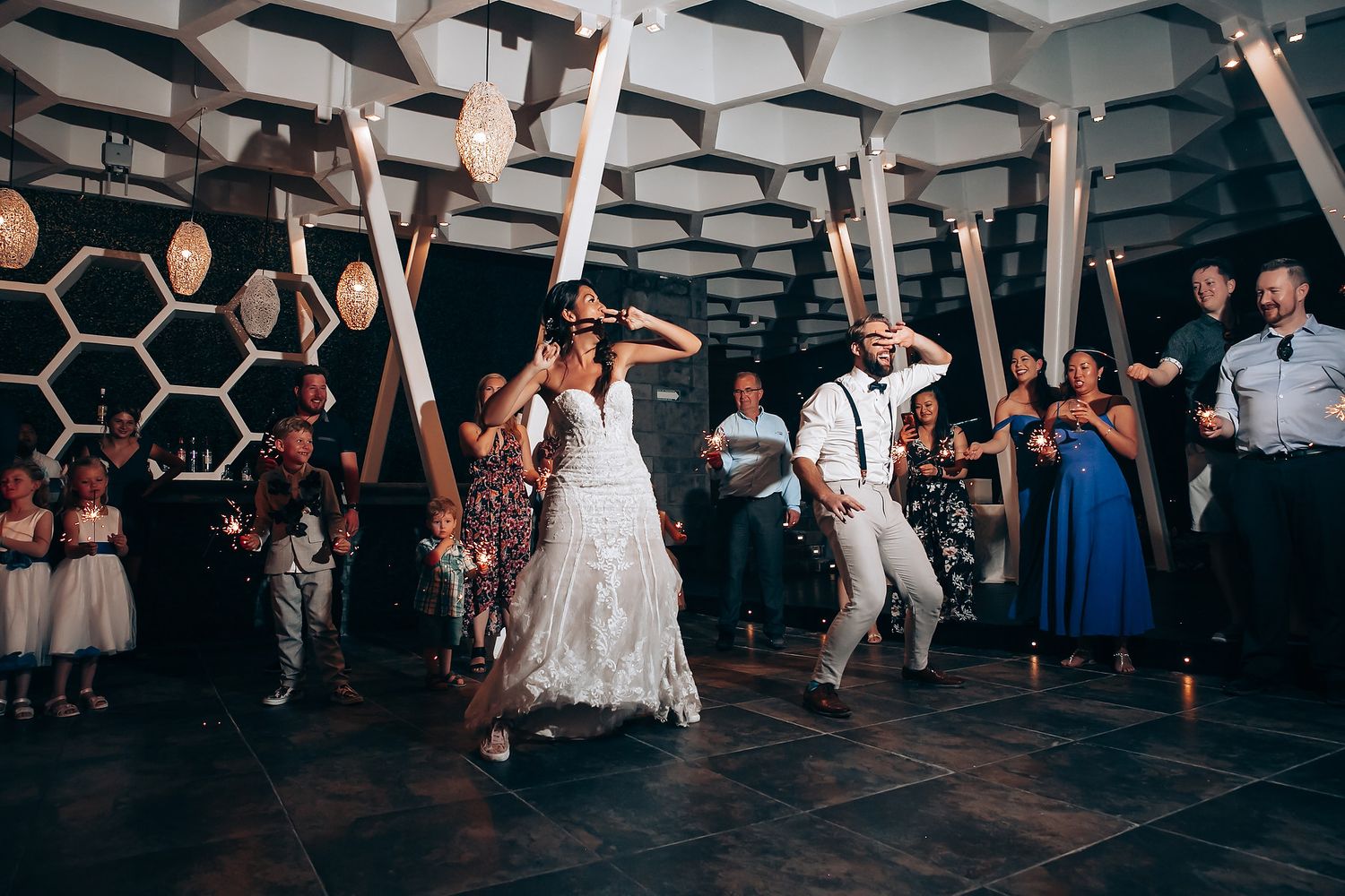 Wedding reception dance floor with modern geometric ceiling design and party atmosphere.
