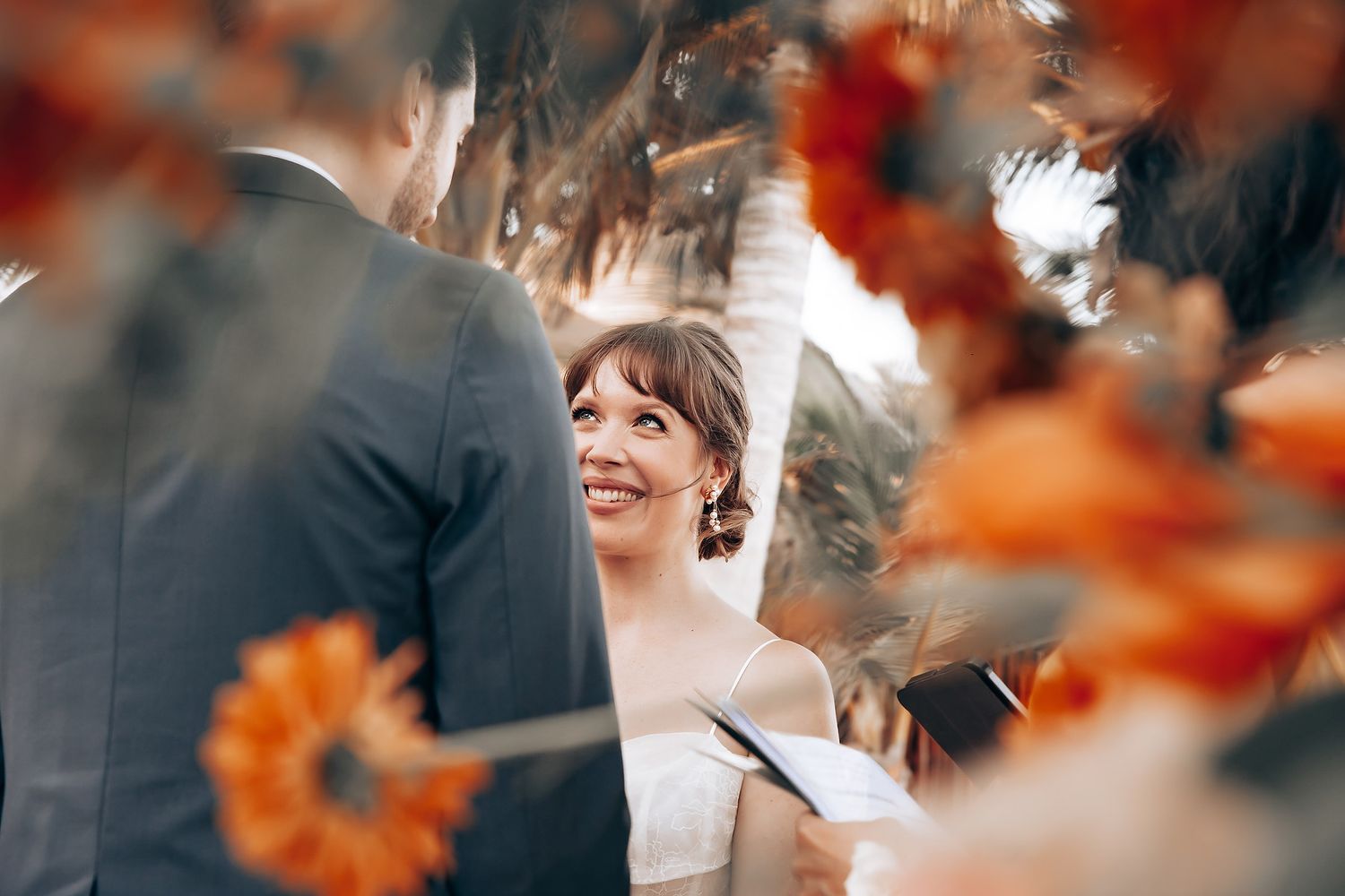 Intimate beach wedding celebration with orange floral accents and natural seaside backdrop.