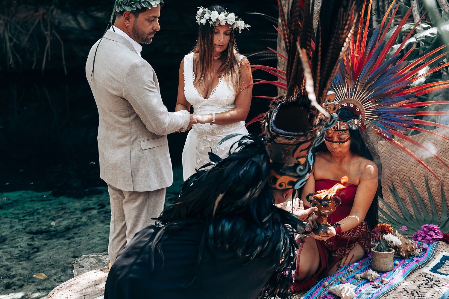 A wedding ceremony in a tropical garden setting with guests and decorative feather displays.