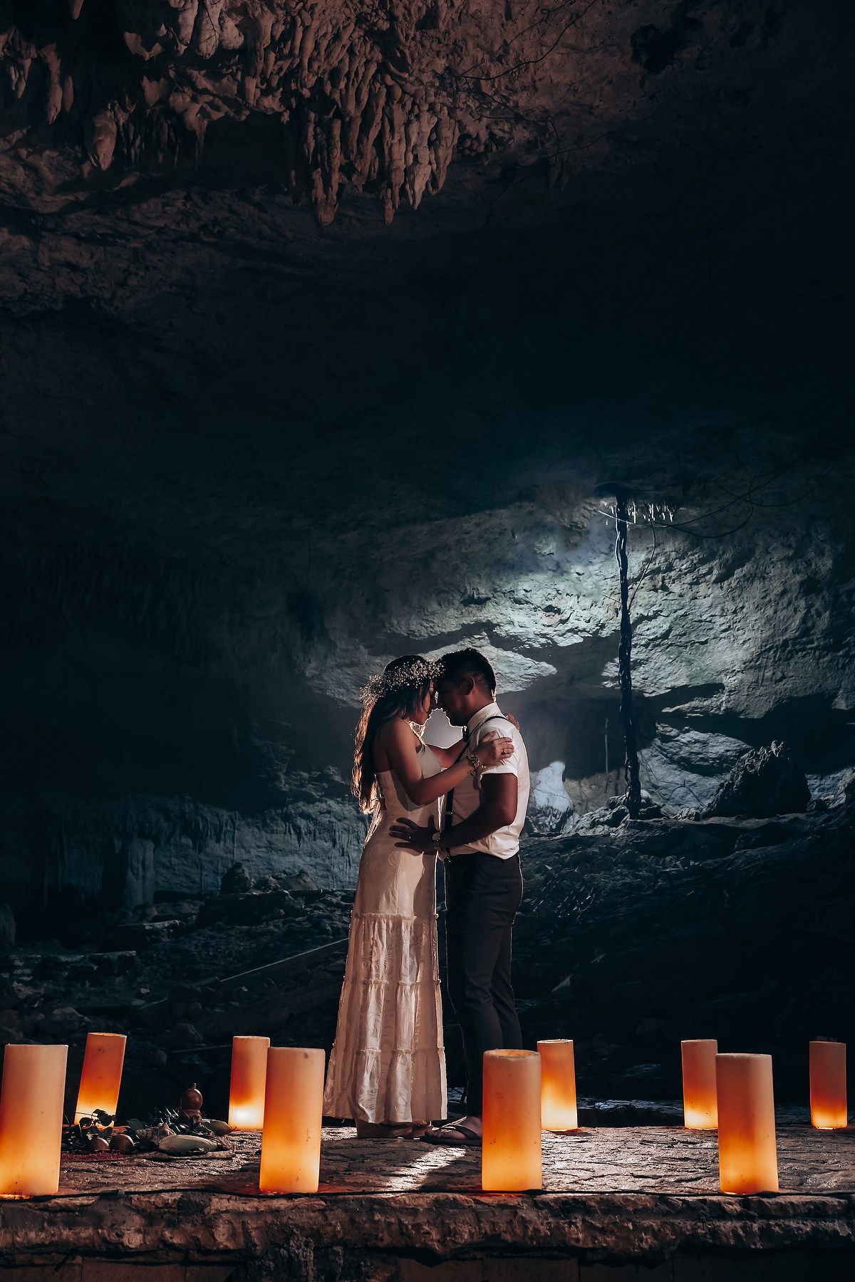 A romantic scene in a cave with illuminated candles lining the ground creating a warm, intimate atmosphere.