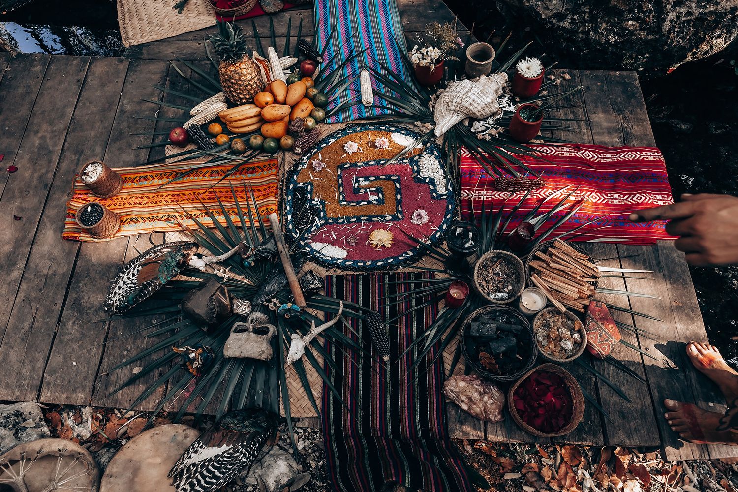 Overhead view of a rustic wooden table set with colorful Moroccan dishes, textiles, candles and traditional decorative elements.