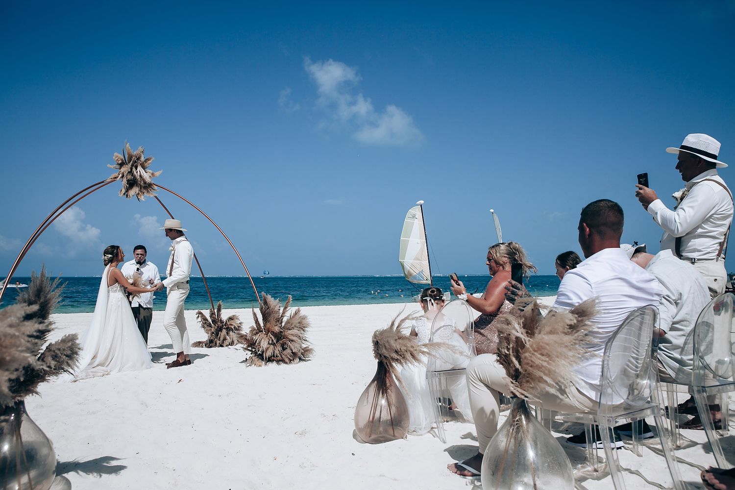 Wedding celebration on a pristine white sand beach with blue ocean waters in the background.