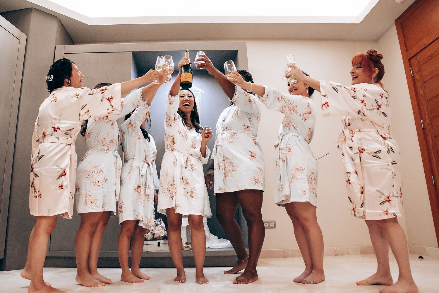 Bridesmaids in floral robes getting ready for a wedding celebration.