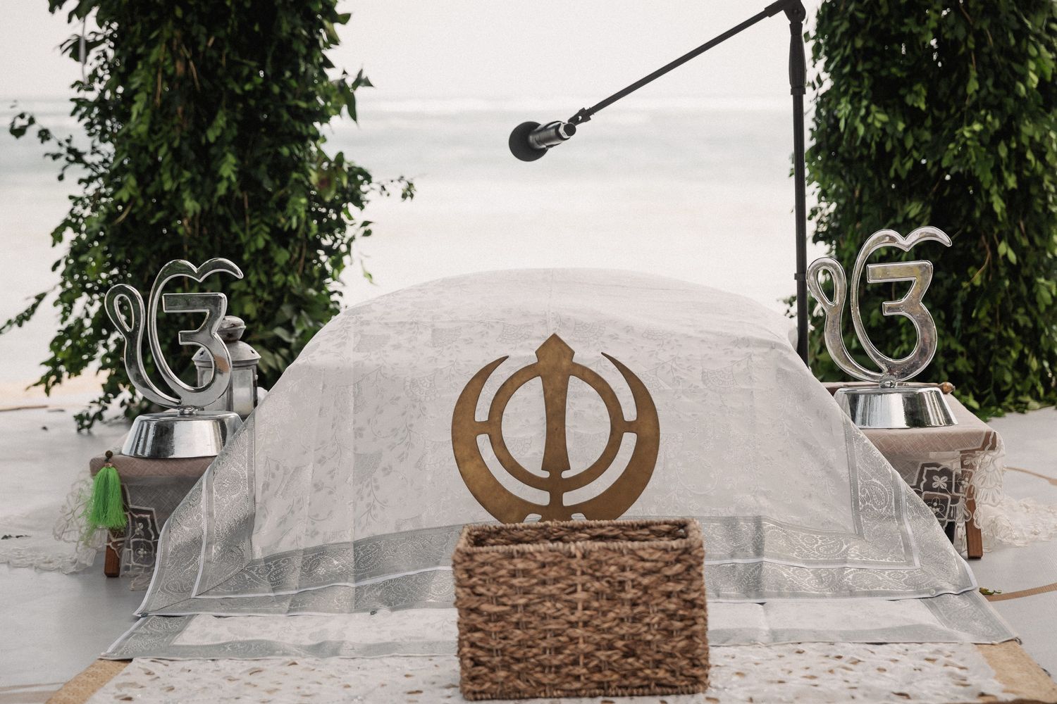 Sikh wedding ceremony setup featuring Khanda symbol and Ik Onkar decorations under a white canopy outdoors.