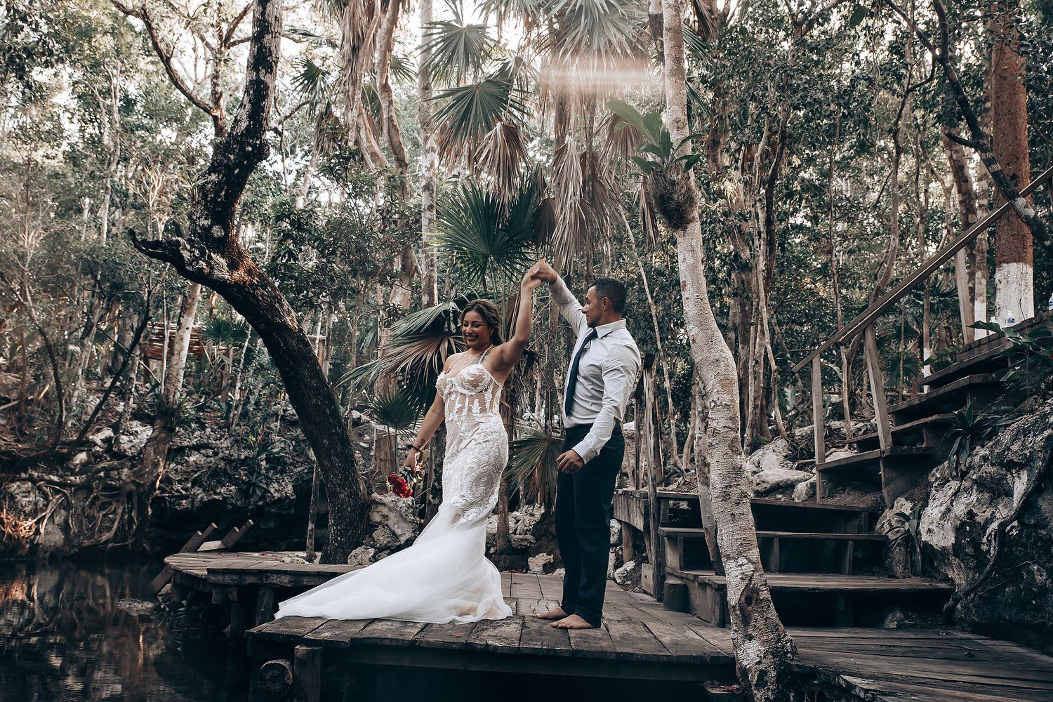 A couple dances beneath towering Spanish moss-draped oak trees in an outdoor garden setting.