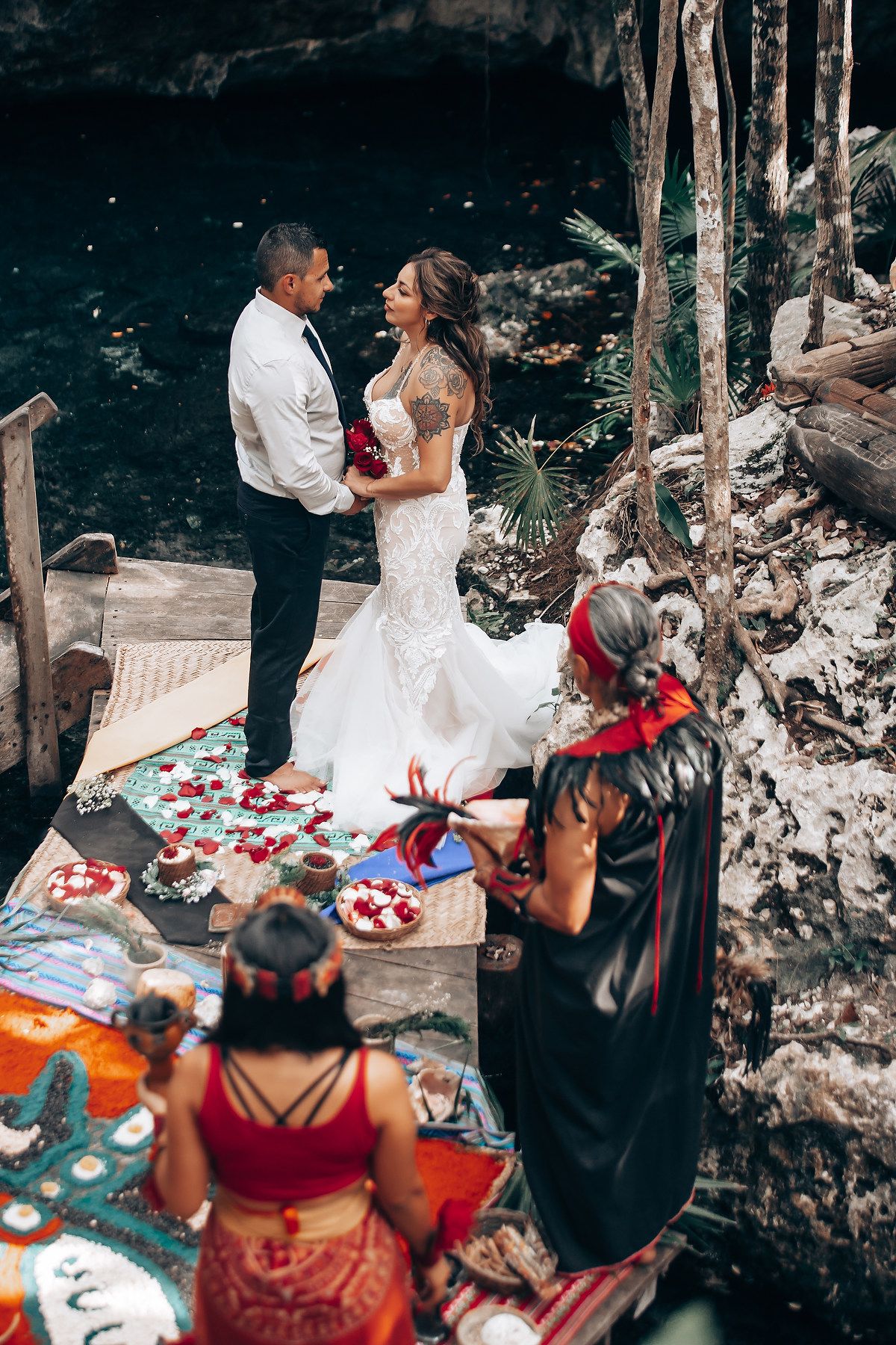 Wedding ceremony with red and white decorations in a cave-like setting surrounded by natural rock formations.