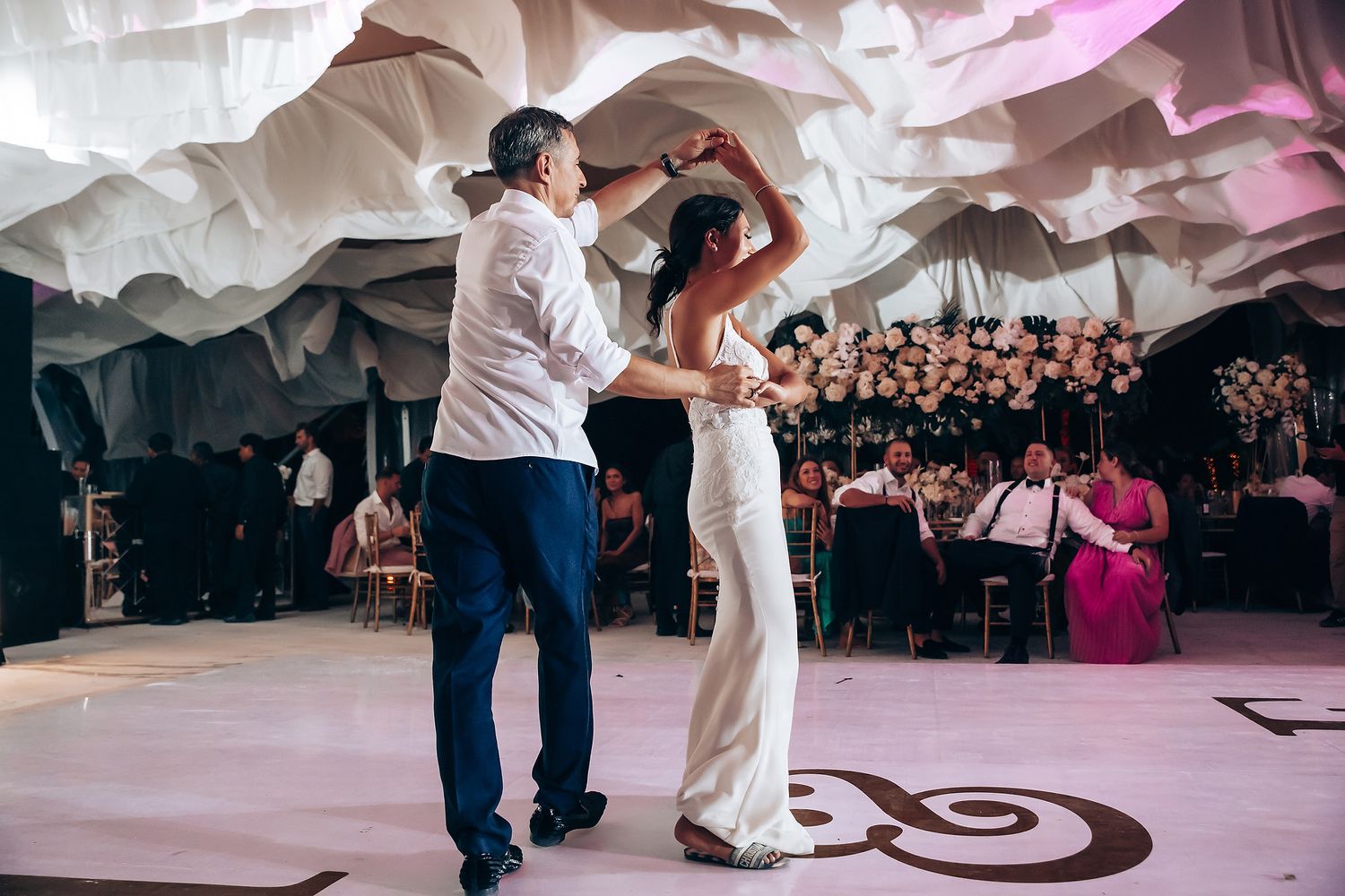 Wedding reception dance floor with draped fabric ceiling and romantic lighting.