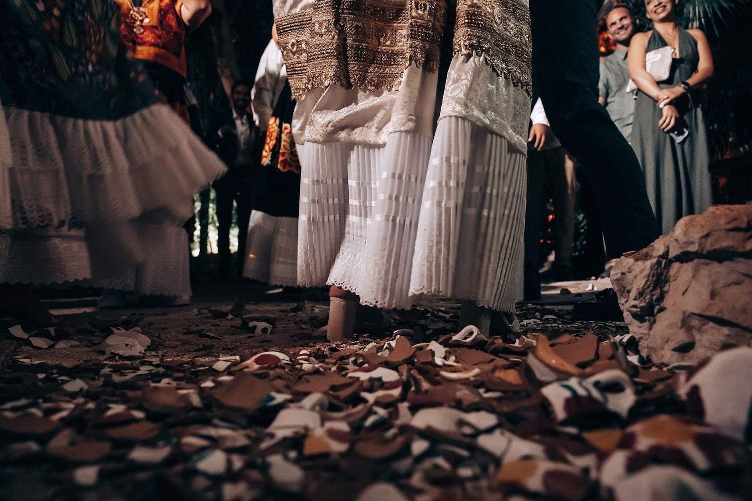 Wedding couple walking through scattered rose petals in romantic lighting.