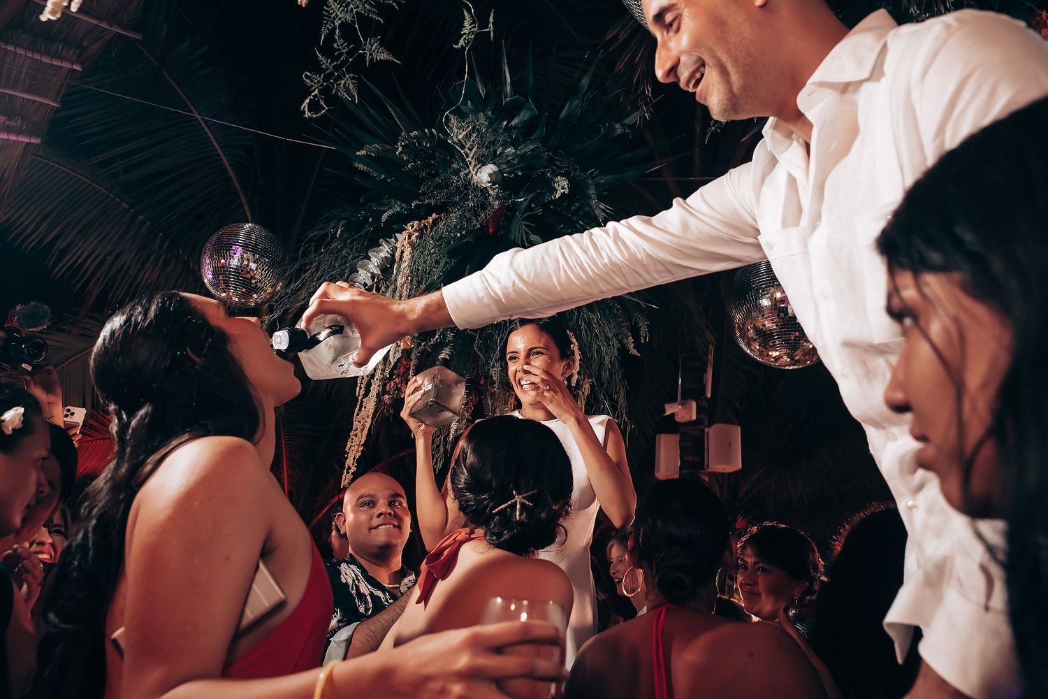 Energetic dance party with guests celebrating on a dark dance floor.
