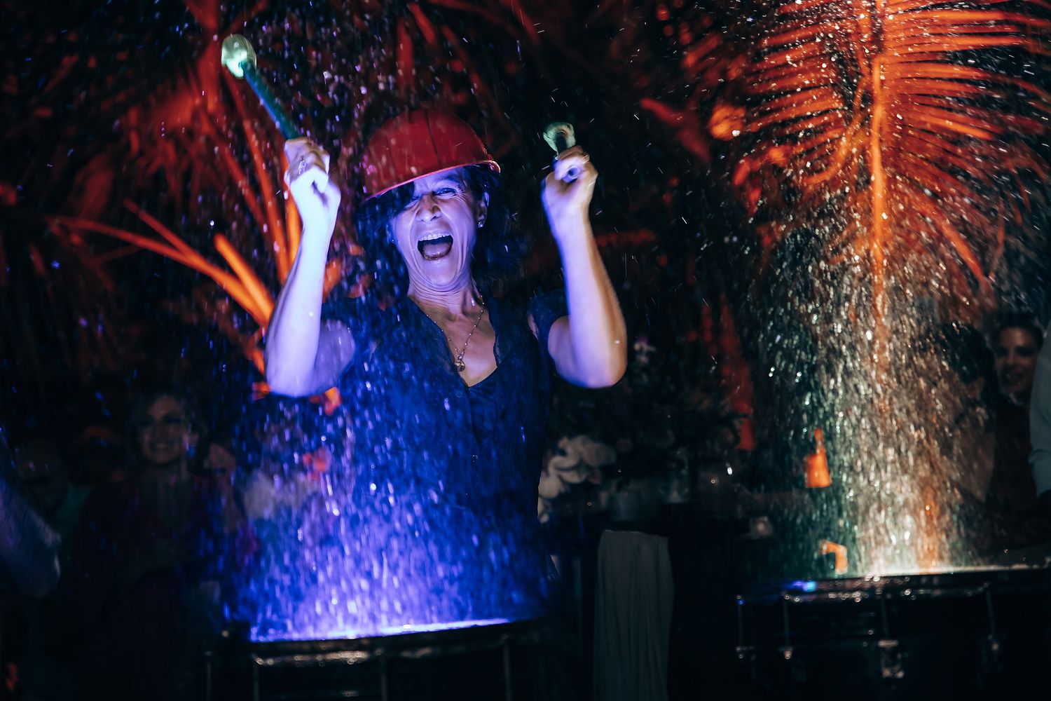 Performer in blue illuminated by dramatic lighting and sparkles during a nighttime show.