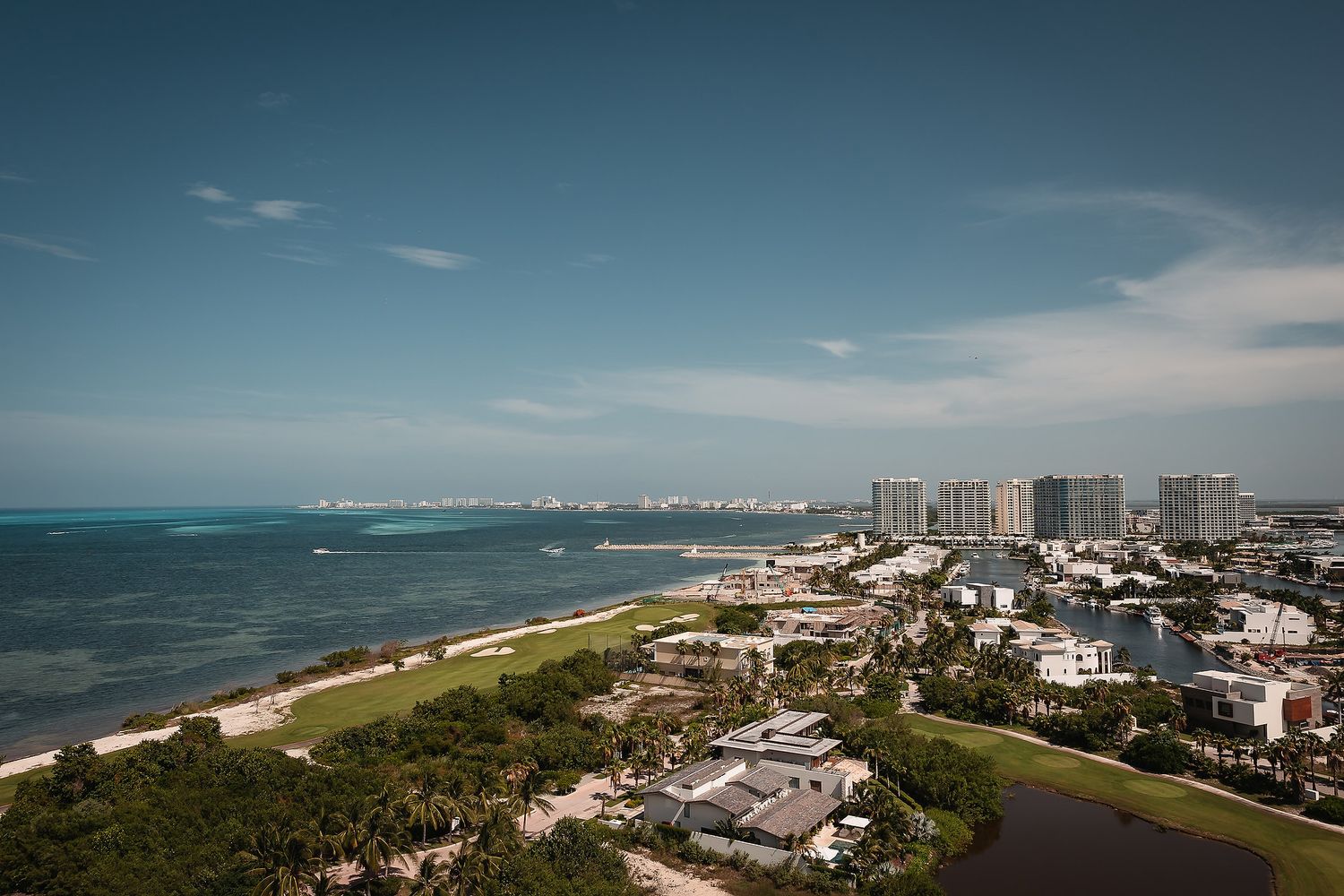 Panoramic coastal cityscape showing beach, buildings and ocean views under blue skies.