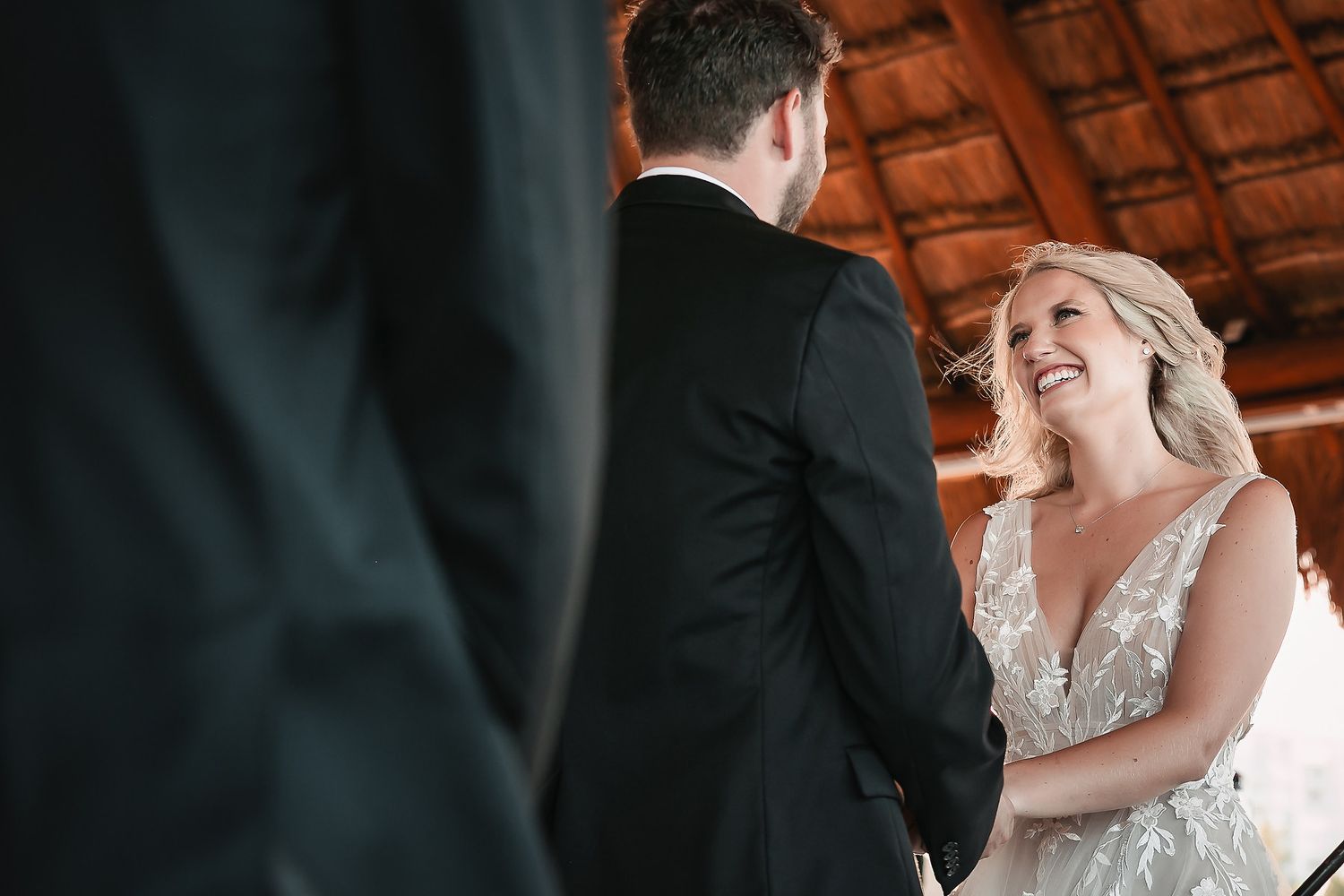 Intimate first look between couple under thatched roof with natural lighting.