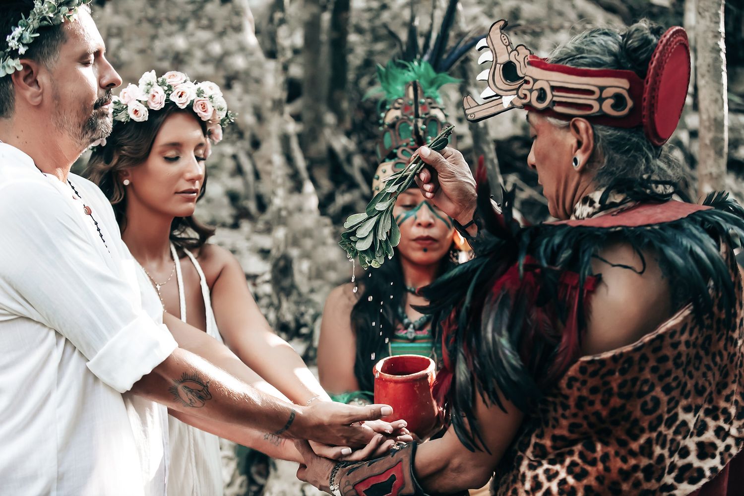 A group of people dressed in traditional attire gather in a lush, natural setting.