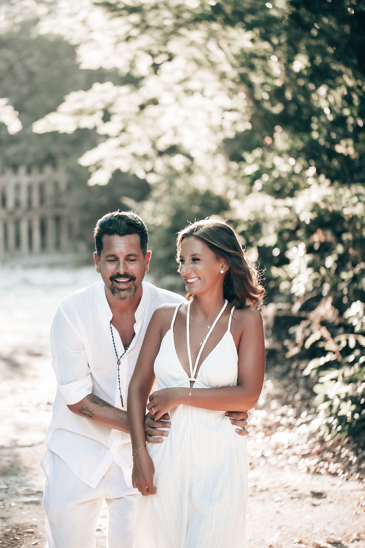 A couple walks together in a picturesque, natural setting with trees in the background.