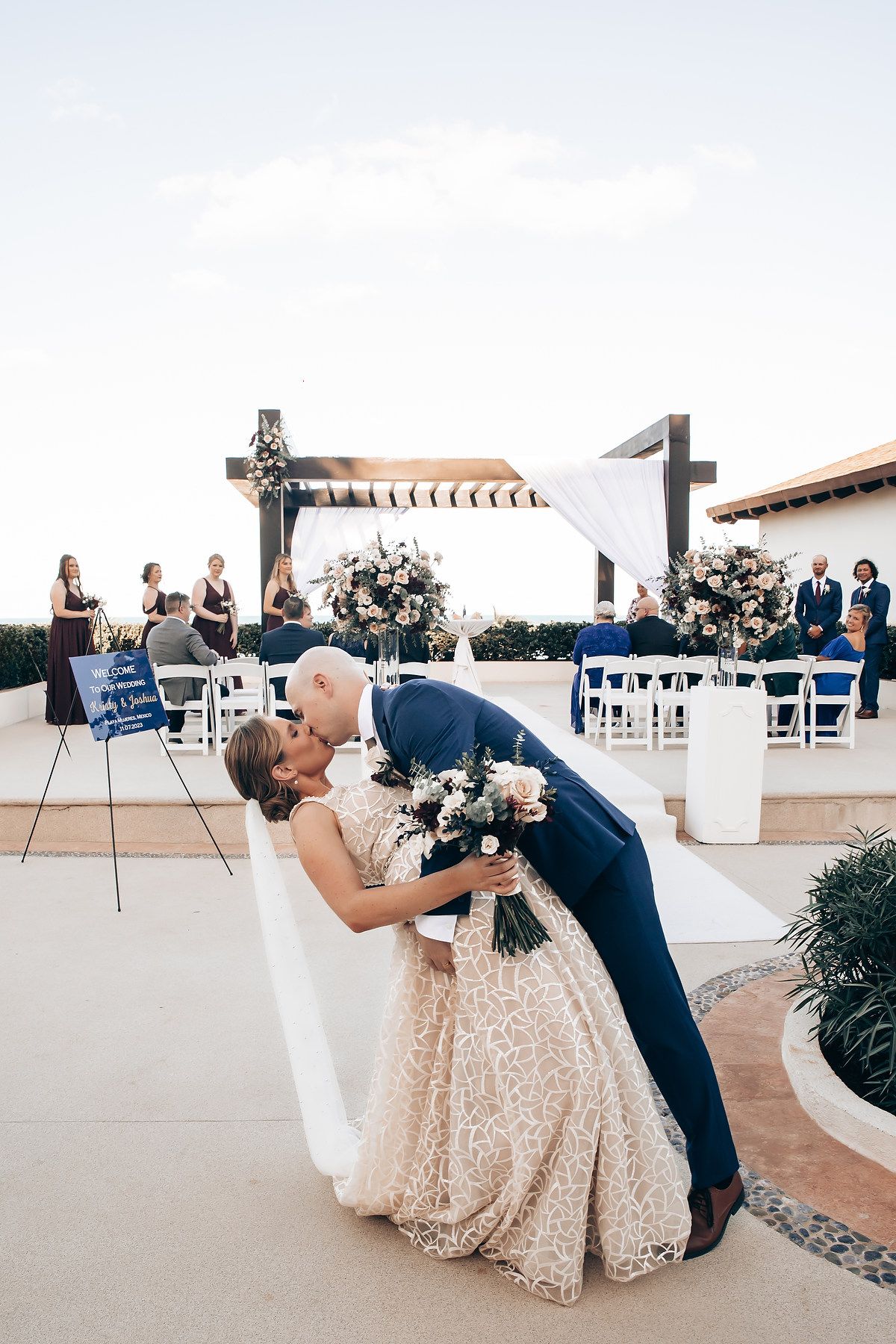 A bride and groom embracing and kissing during their wedding ceremony.