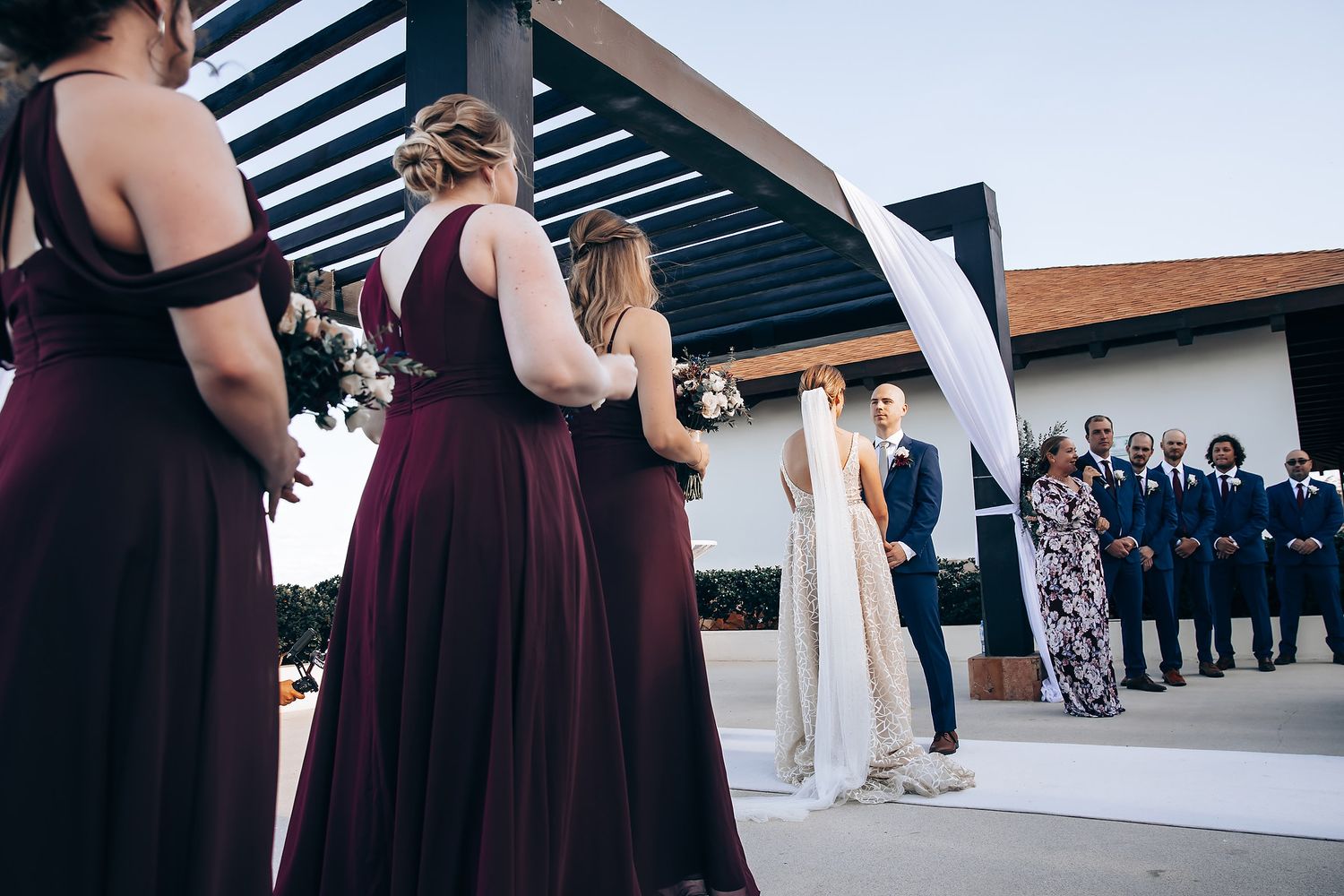 A bride and groom standing at the altar, surrounded by their wedding party in formal attire.