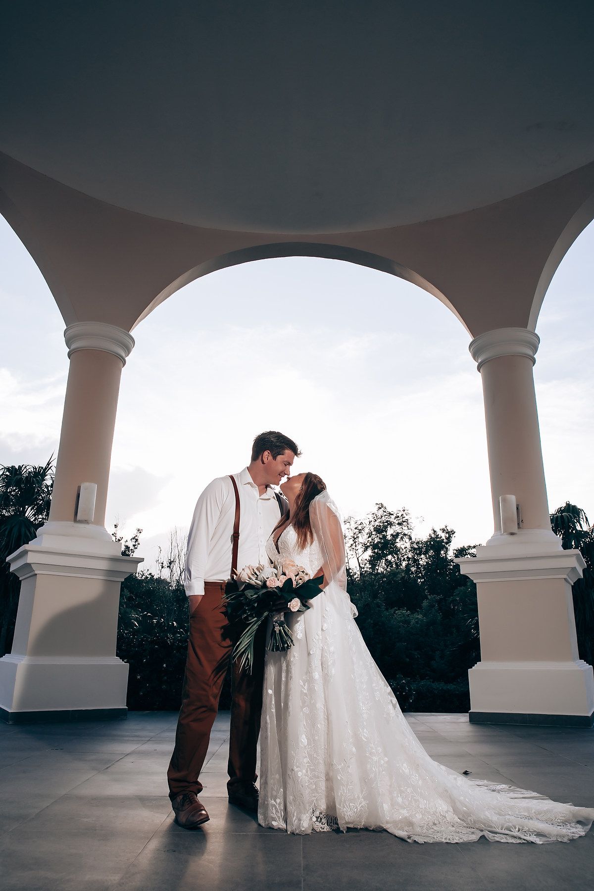 Romantic wedding photo shoot under white archways at dusk.