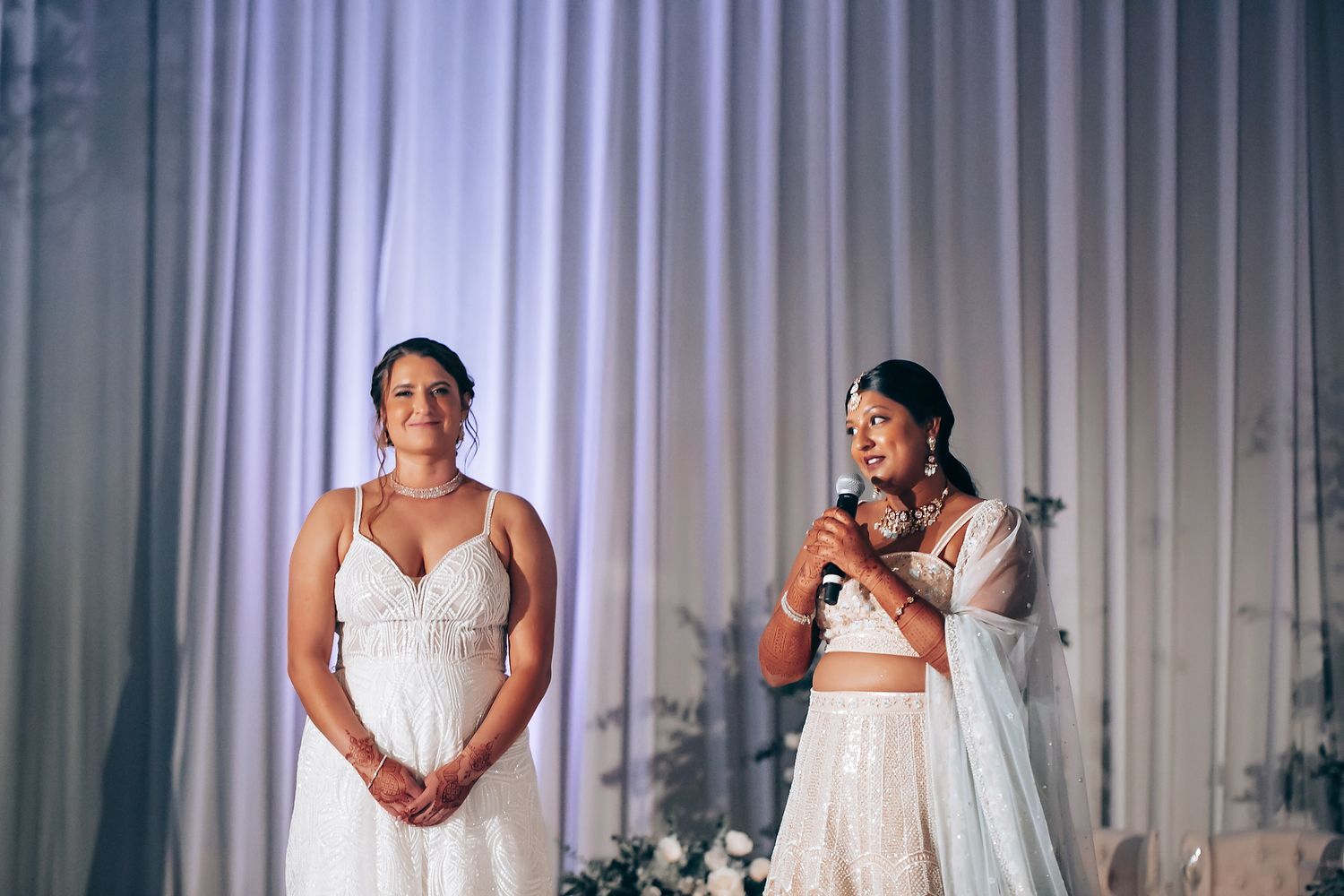 Wedding ceremony setup with white curtains and elegant decor in an indoor venue.