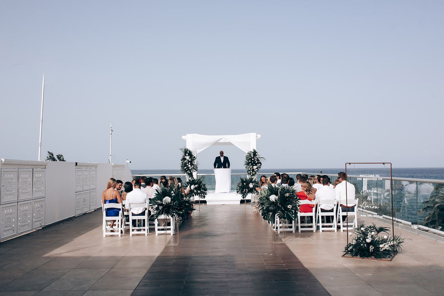 Modern white wedding ceremony space overlooking the ocean with guest seating.