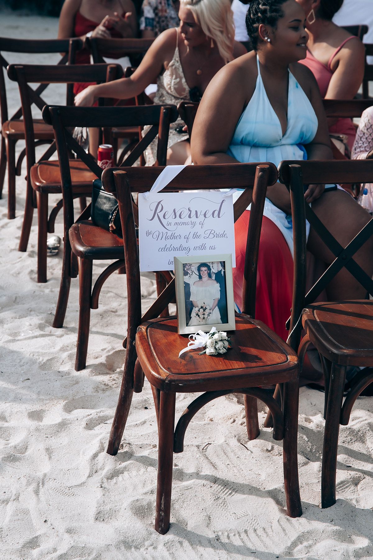 Wooden chairs arranged on beach sand with reserved sign for wedding ceremony.