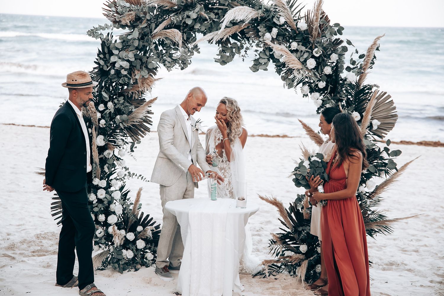 Seaside wedding celebration with floral arch and natural beach backdrop.