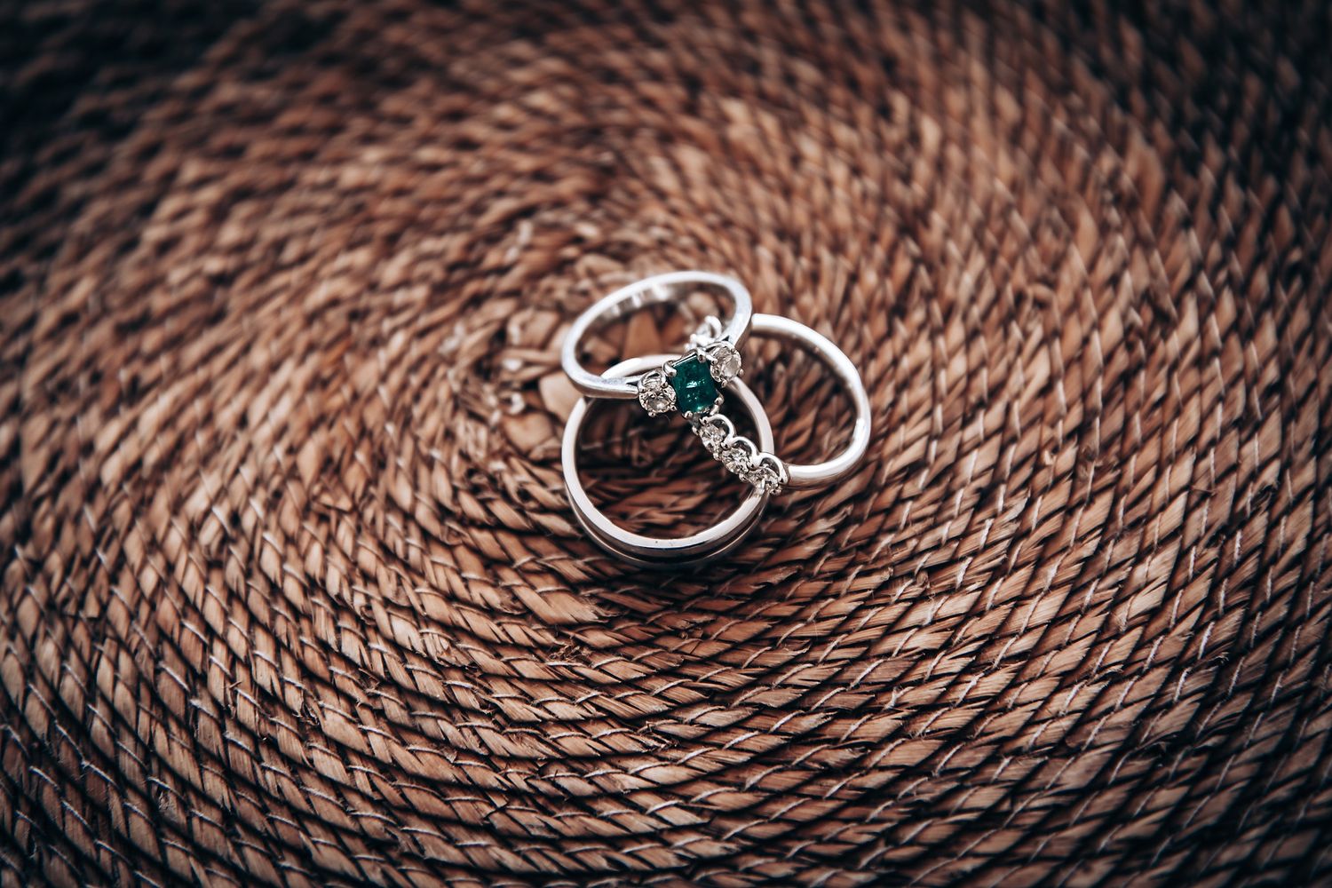 Close up macro shots of silver rings on a brown woven rope texture showing different angles and details.