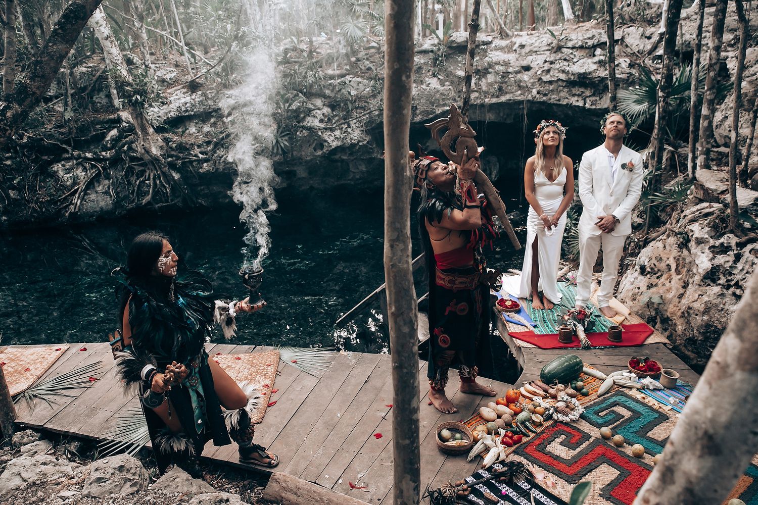 Forest wedding ceremony setup with decorative rugs and smoke elements creating mystical atmosphere.