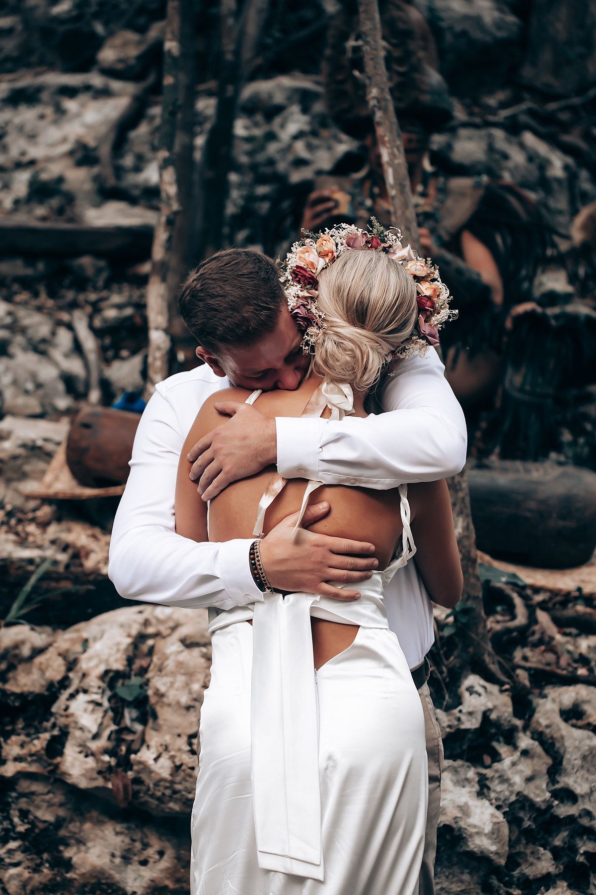 Intimate embrace captured during wedding ceremony in natural cave setting.